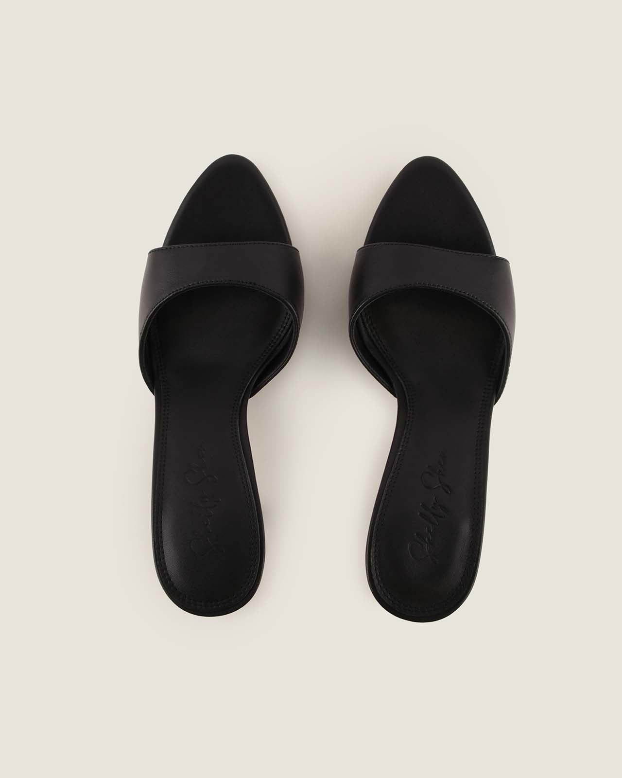 Pair of black sandals on a light beige background