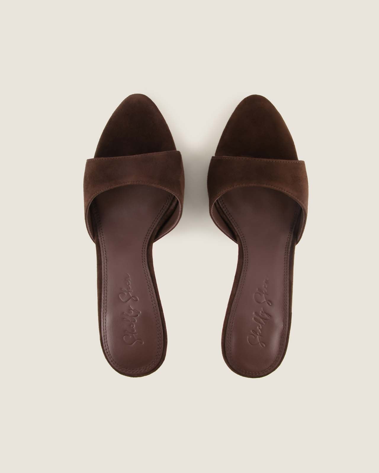 Pair of brown suede sandals on a beige background