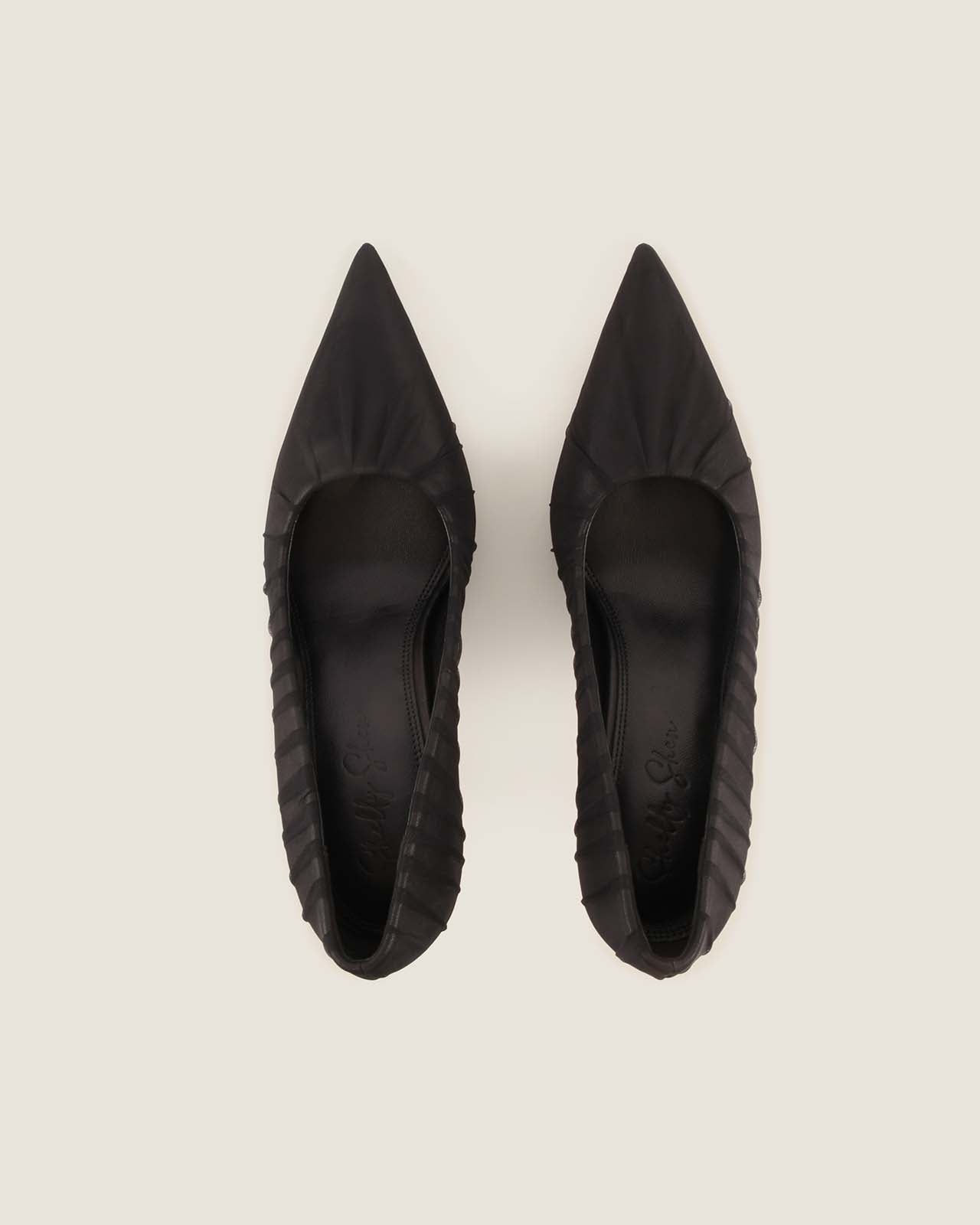 Pair of black pointed-toe shoes on a light gray background