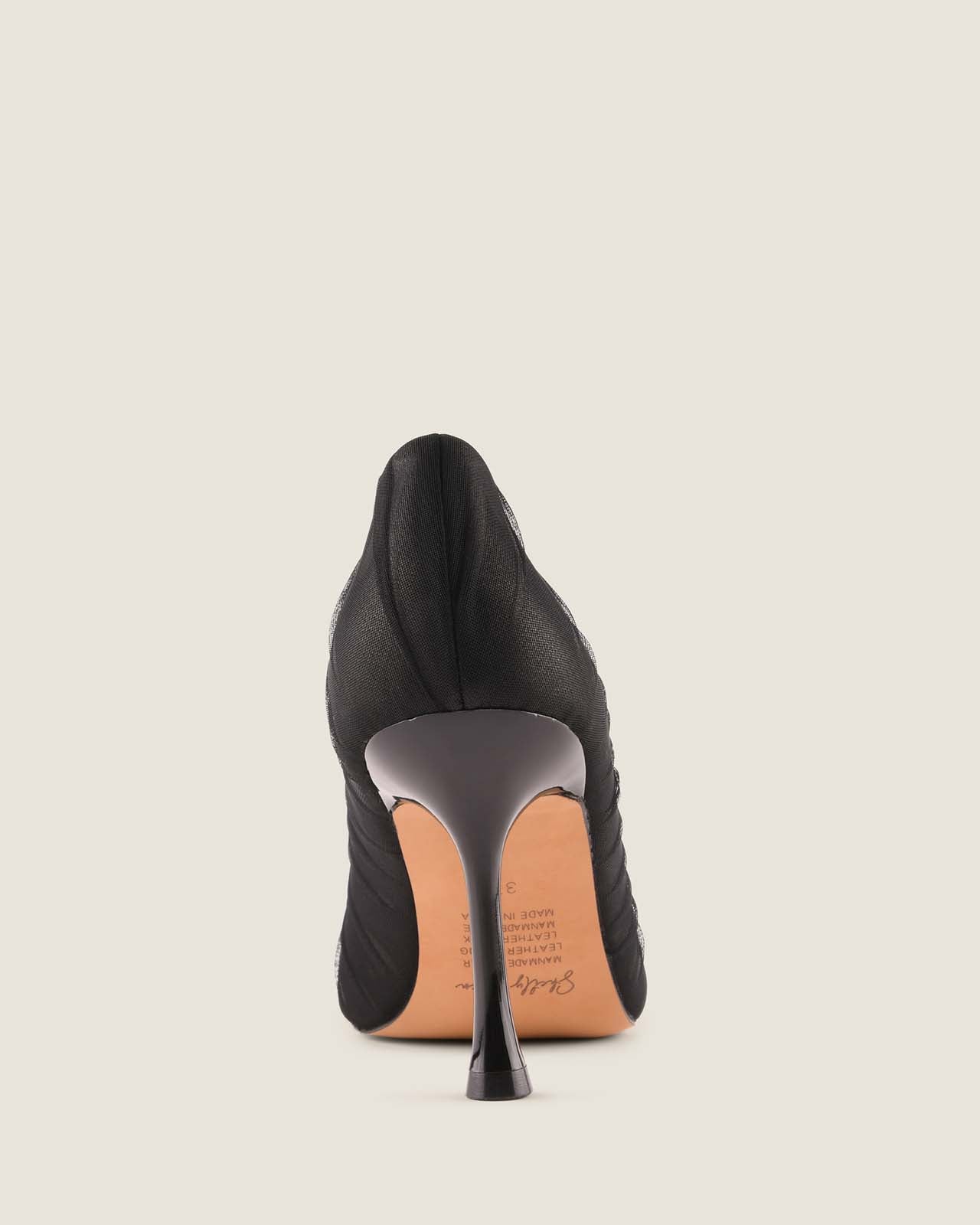 Back of a black high-heeled shoe on a beige background