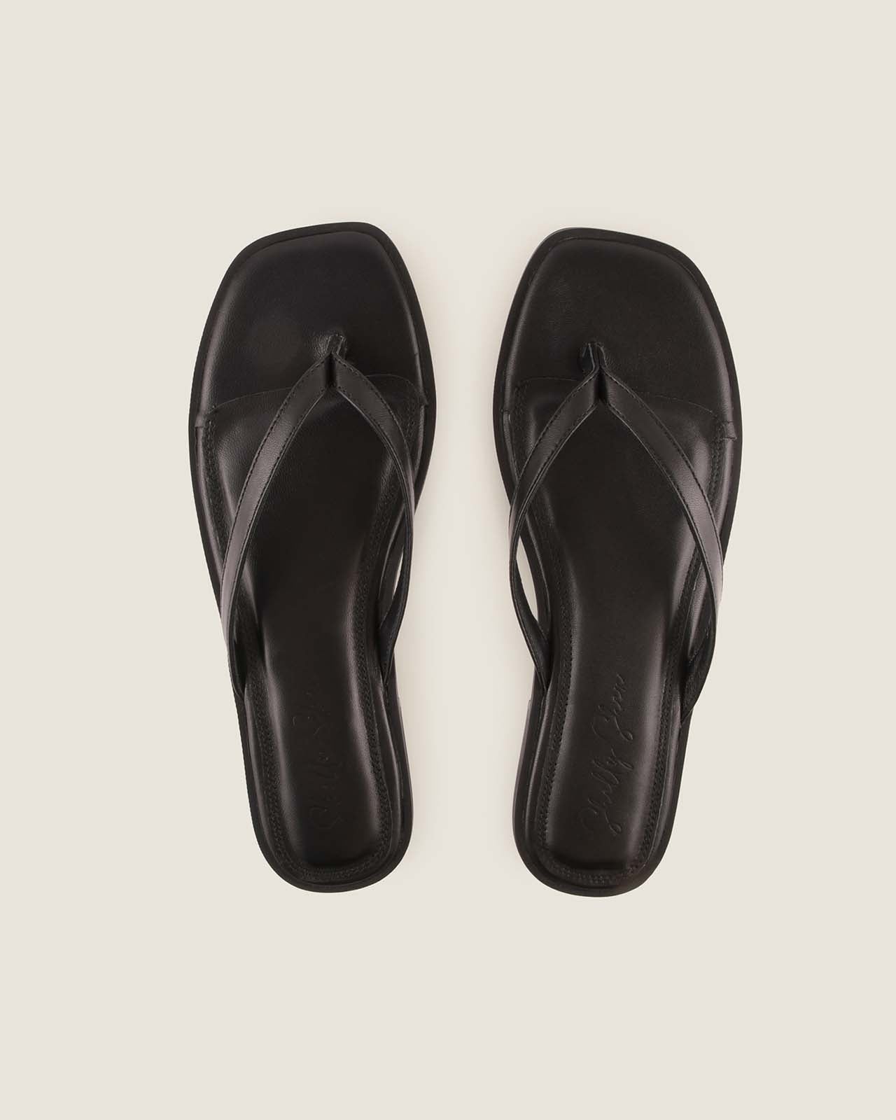 Pair of Black Leather Flat Sandals on a Light Grey Background