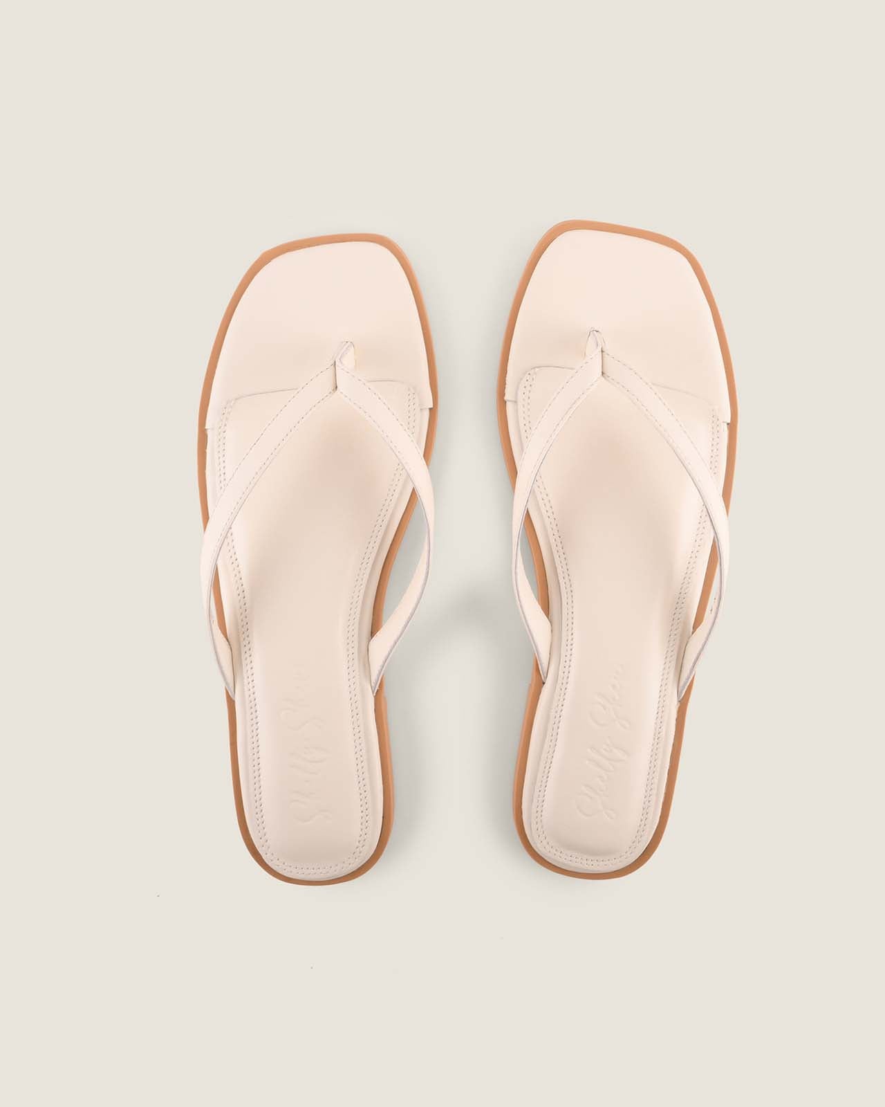 Pair of White Leather Aspen Flat Sandals on a light grey background