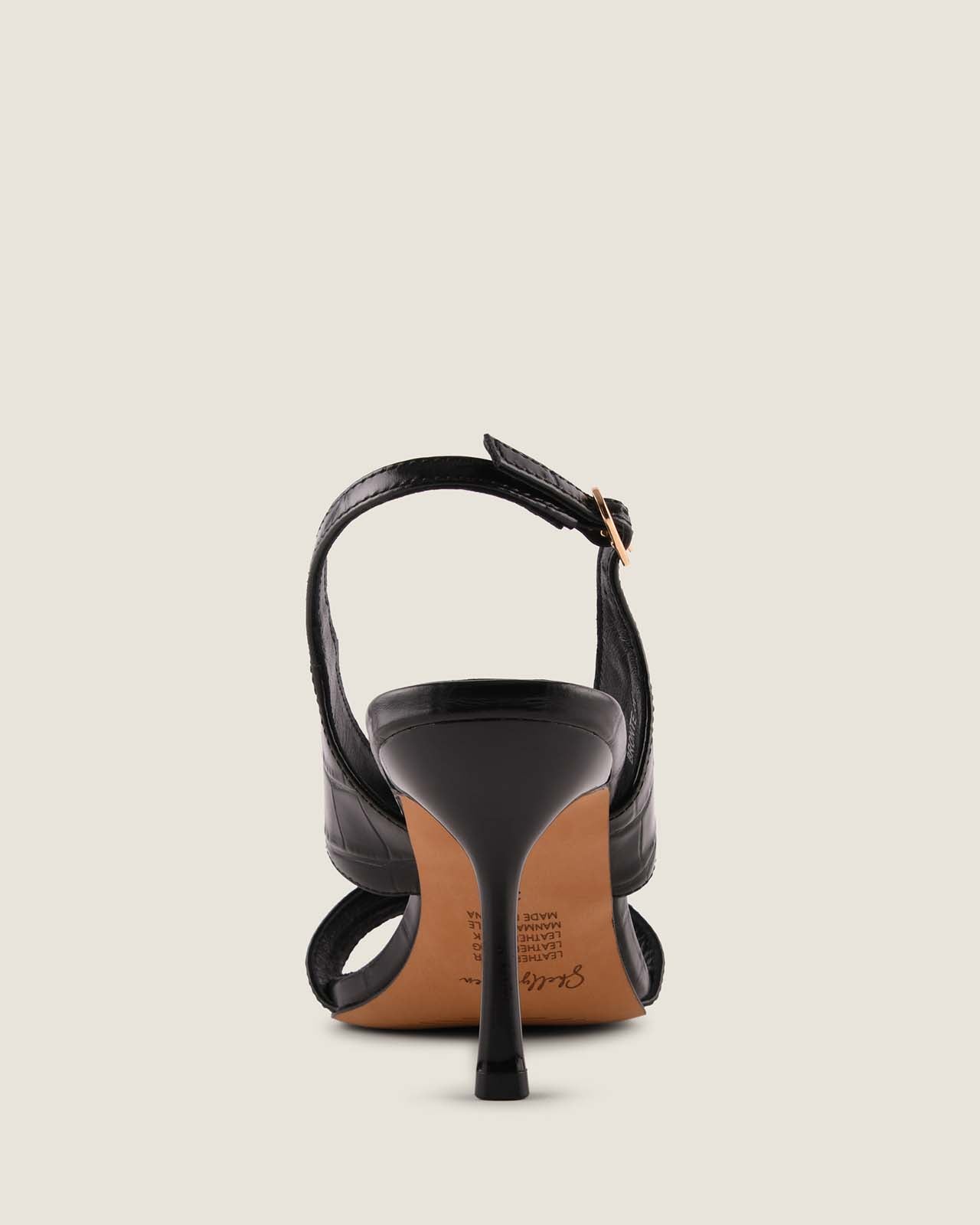 Back of black high-heeled sandal on a light beige background