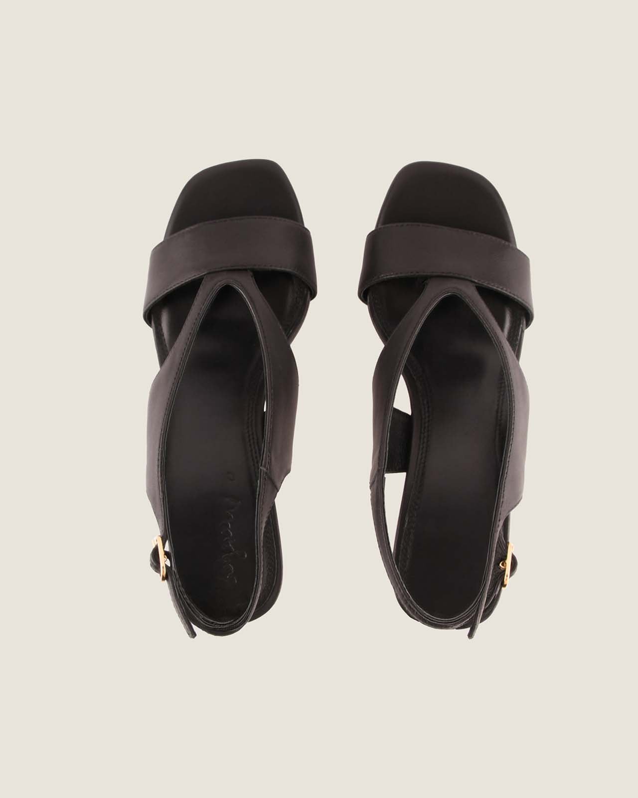 Pair of black high-heeled sandals on a light beige background
