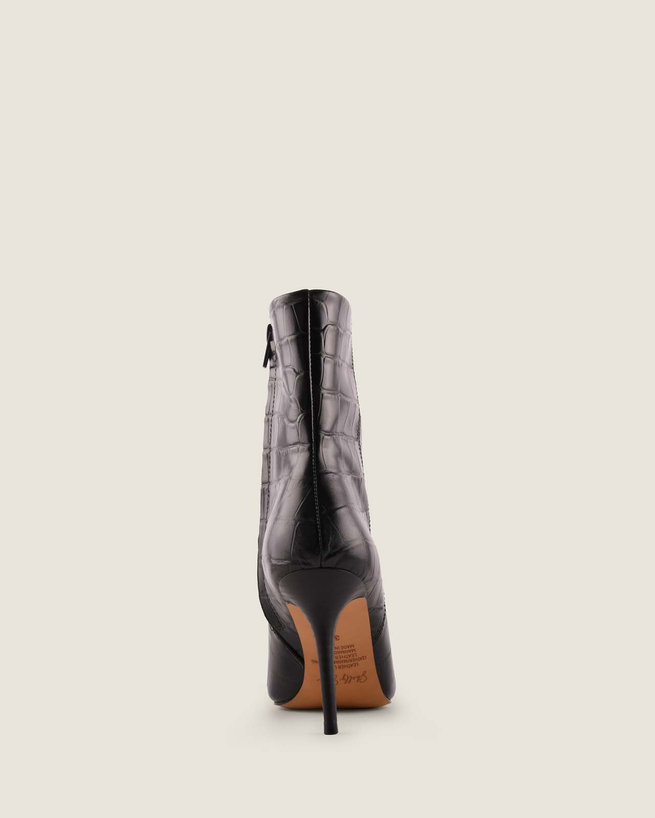 Black crocodile-patterned high-heeled boot on a light beige background