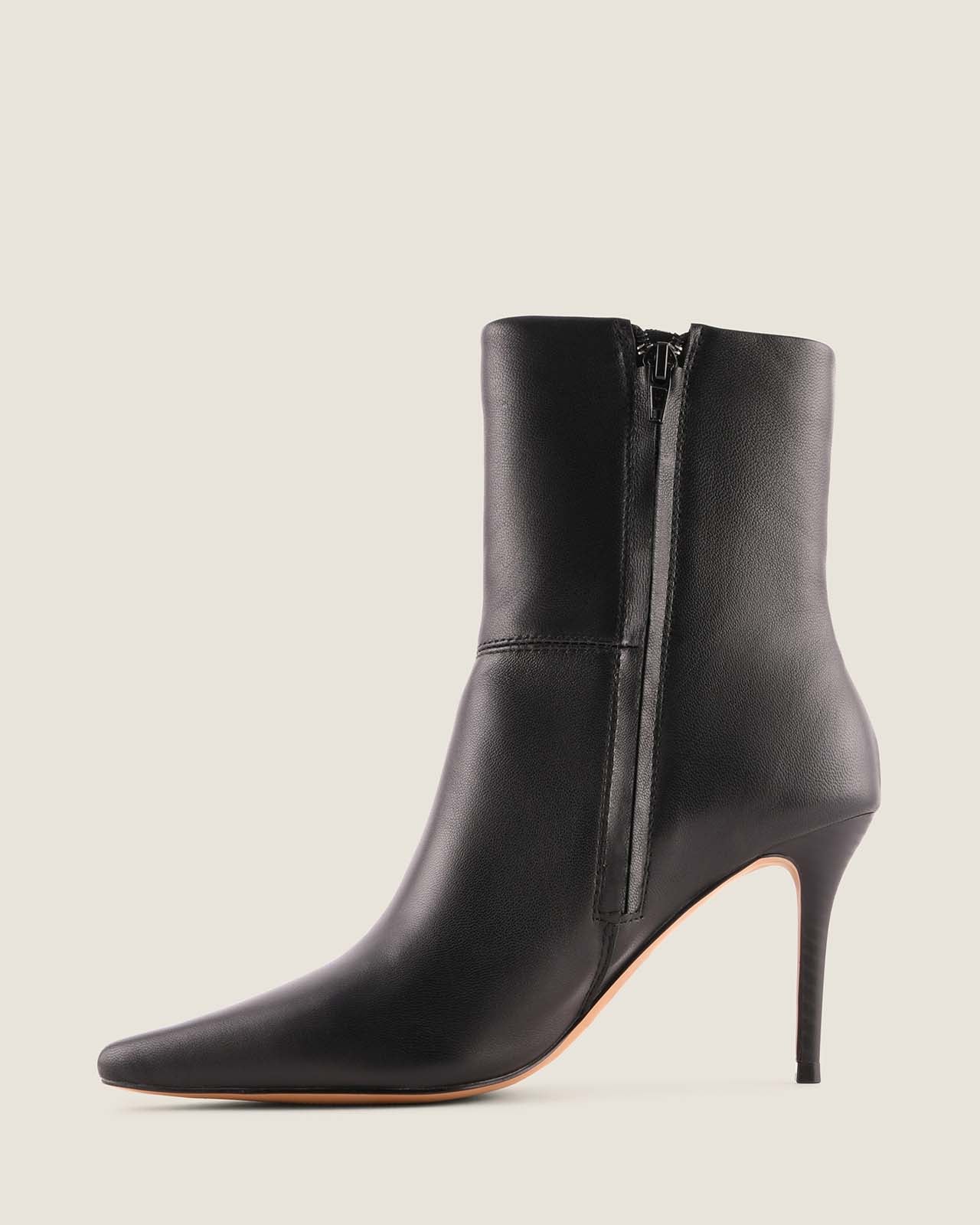Black high-heeled ankle boot with a zipper on a beige background