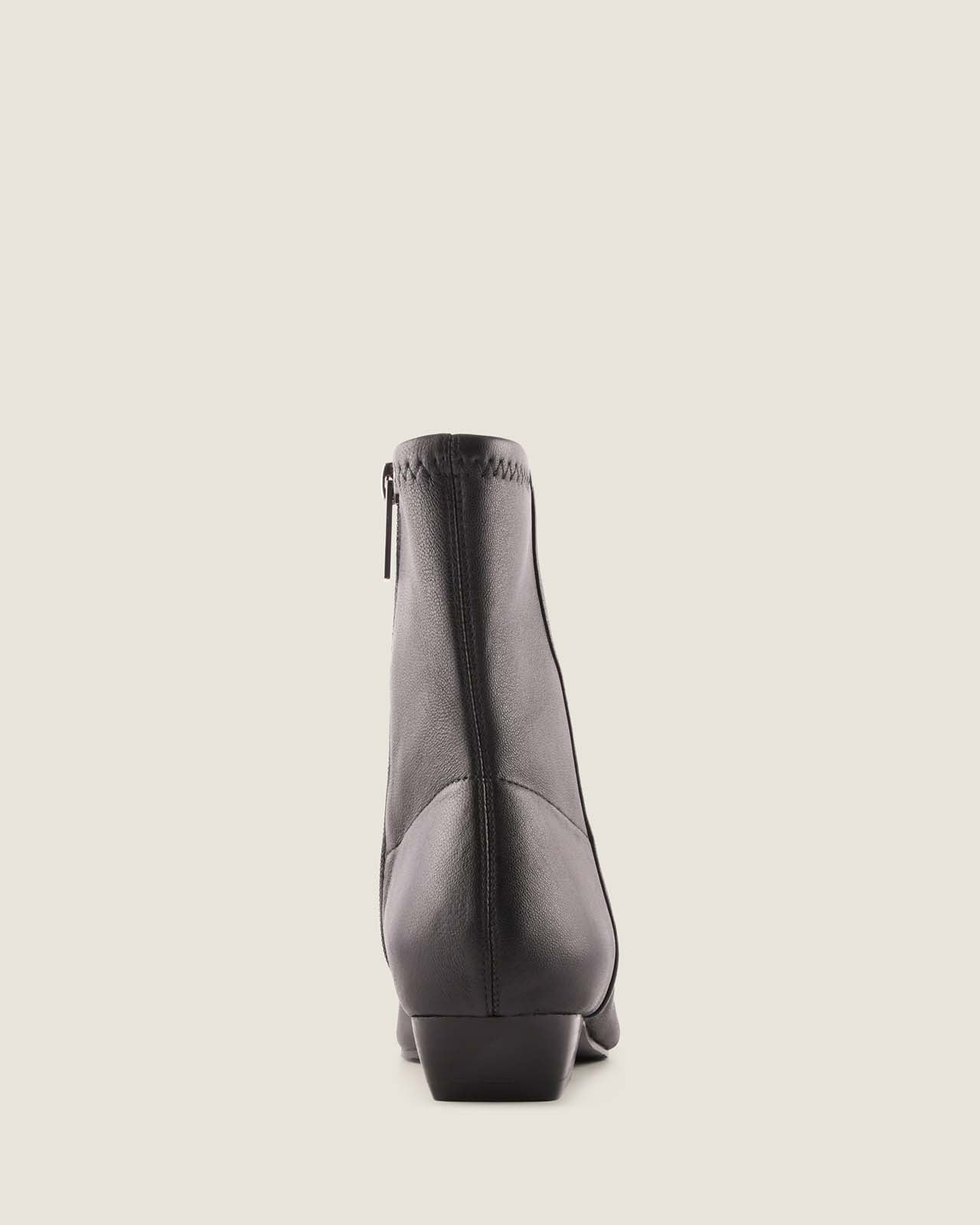 Black ankle boot on a light beige background