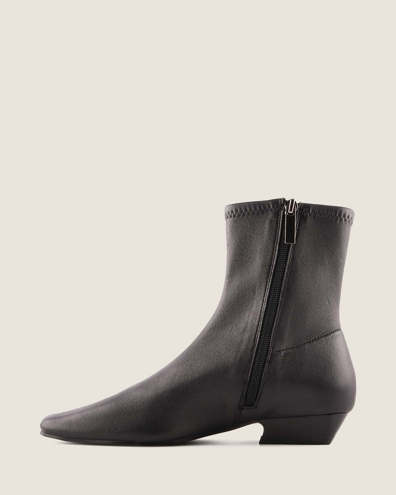 Black ankle boot with a zipper on a light gray background