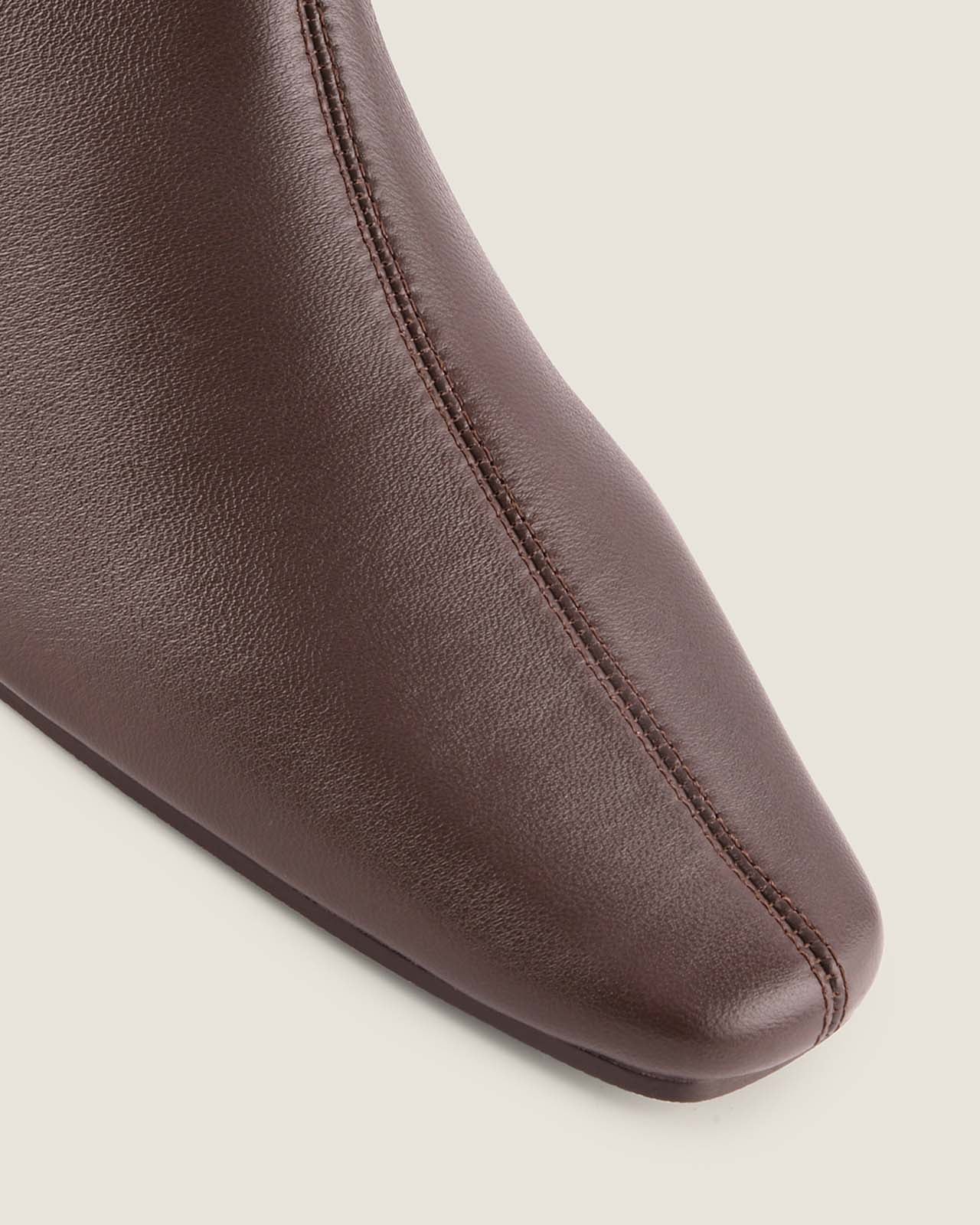 Brown leather ankle boot on a beige background