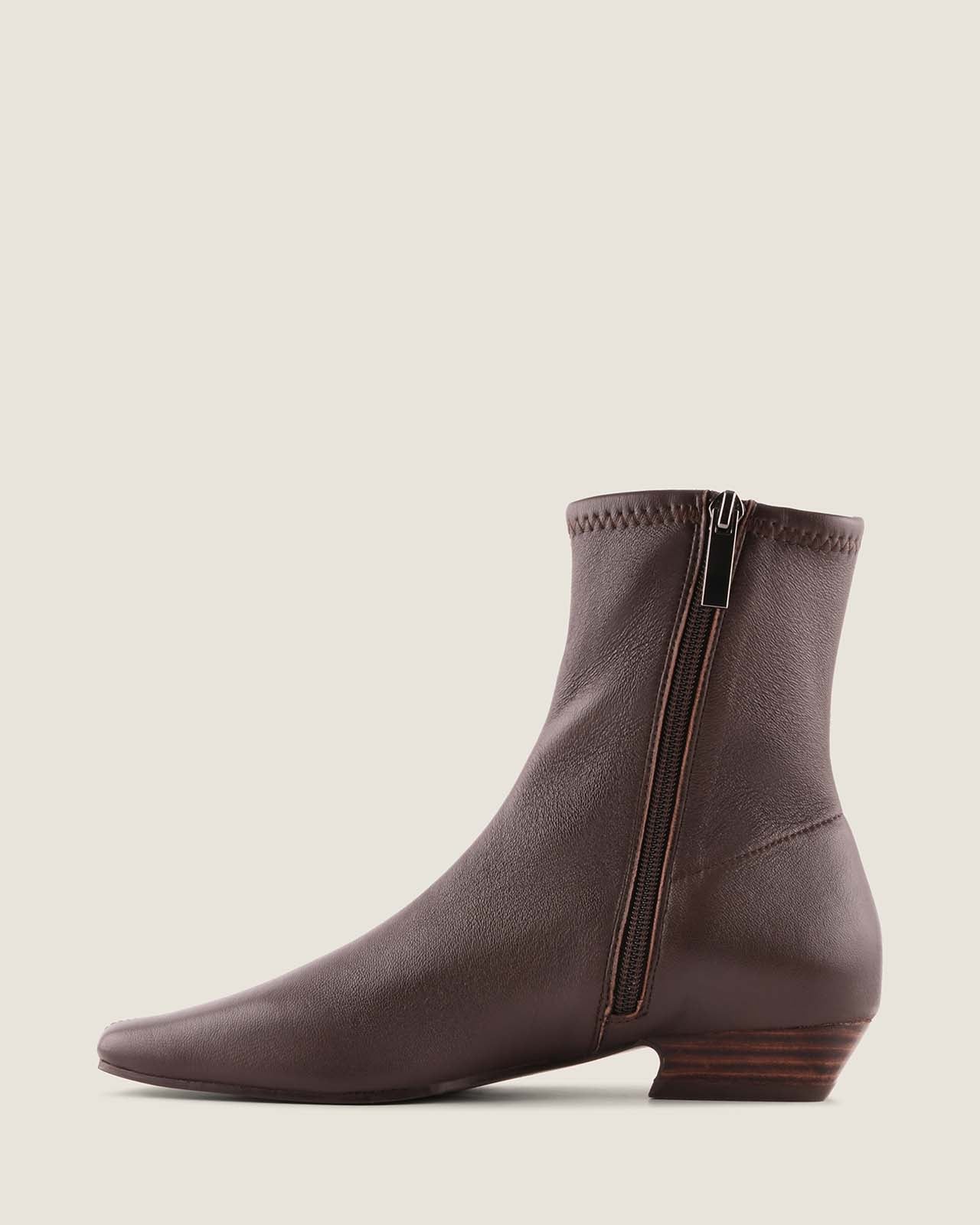 Brown leather ankle boot with a zipper on a light beige background