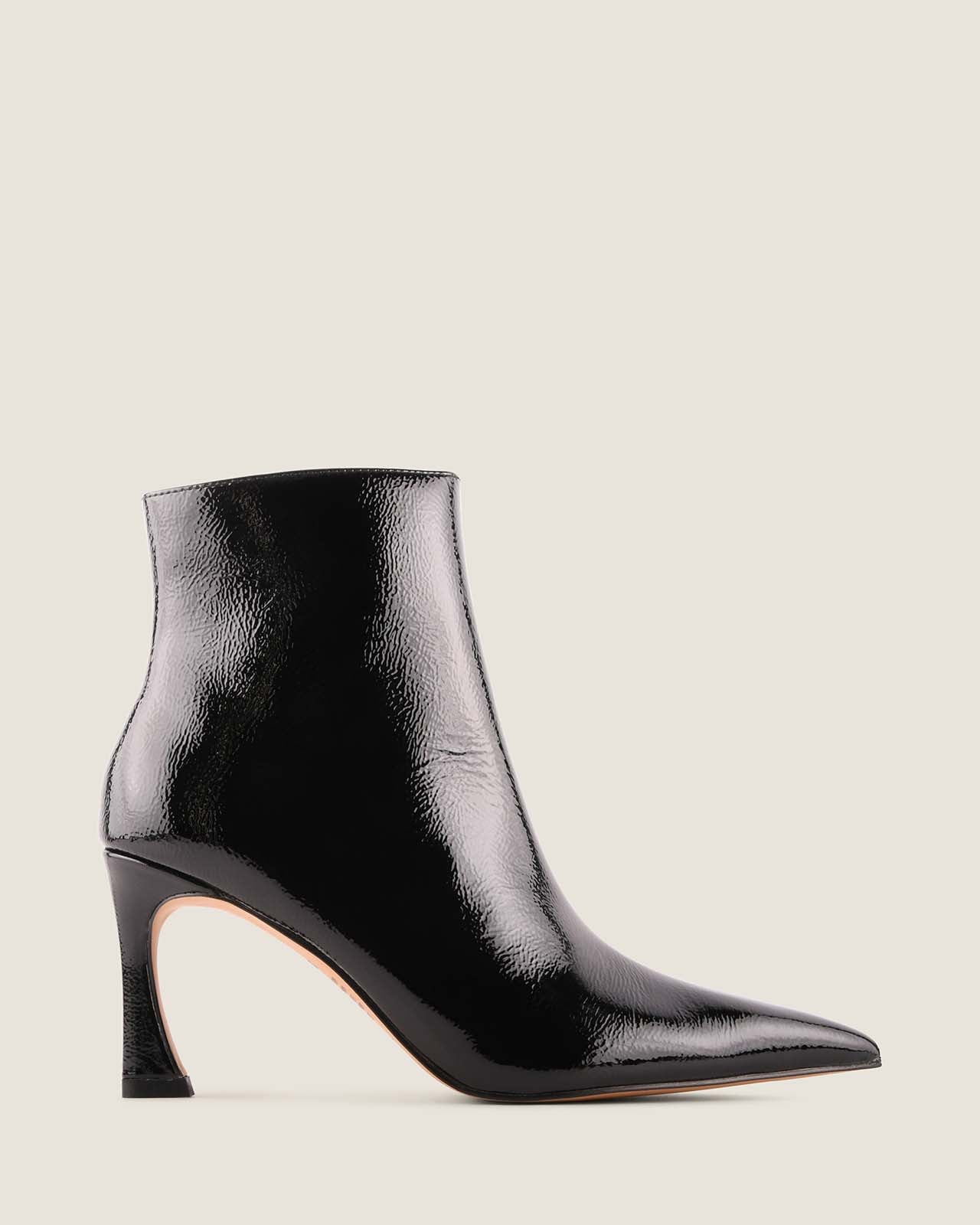 Black patent leather ankle boot on a light beige background