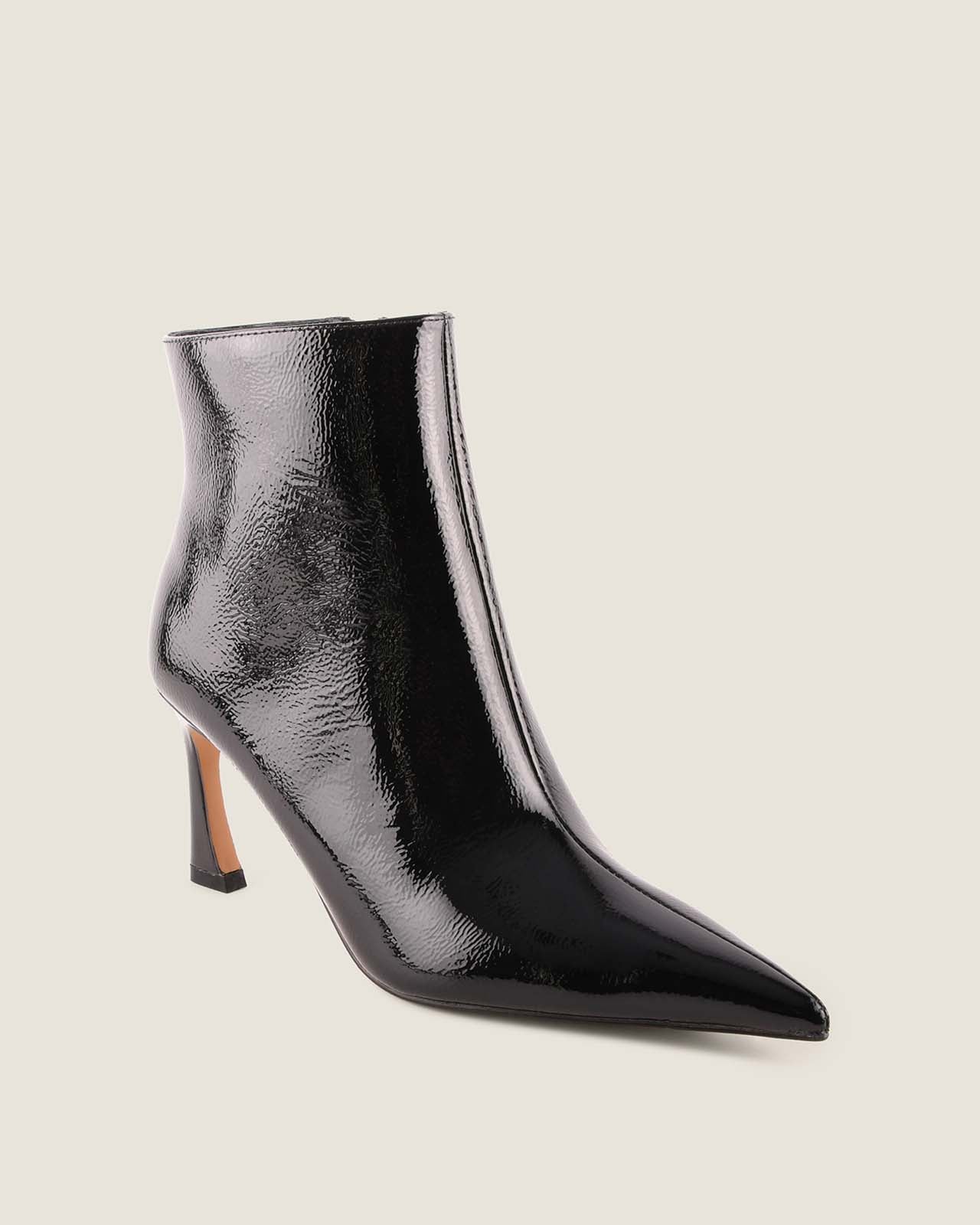 Black patent leather ankle boot on a light beige background