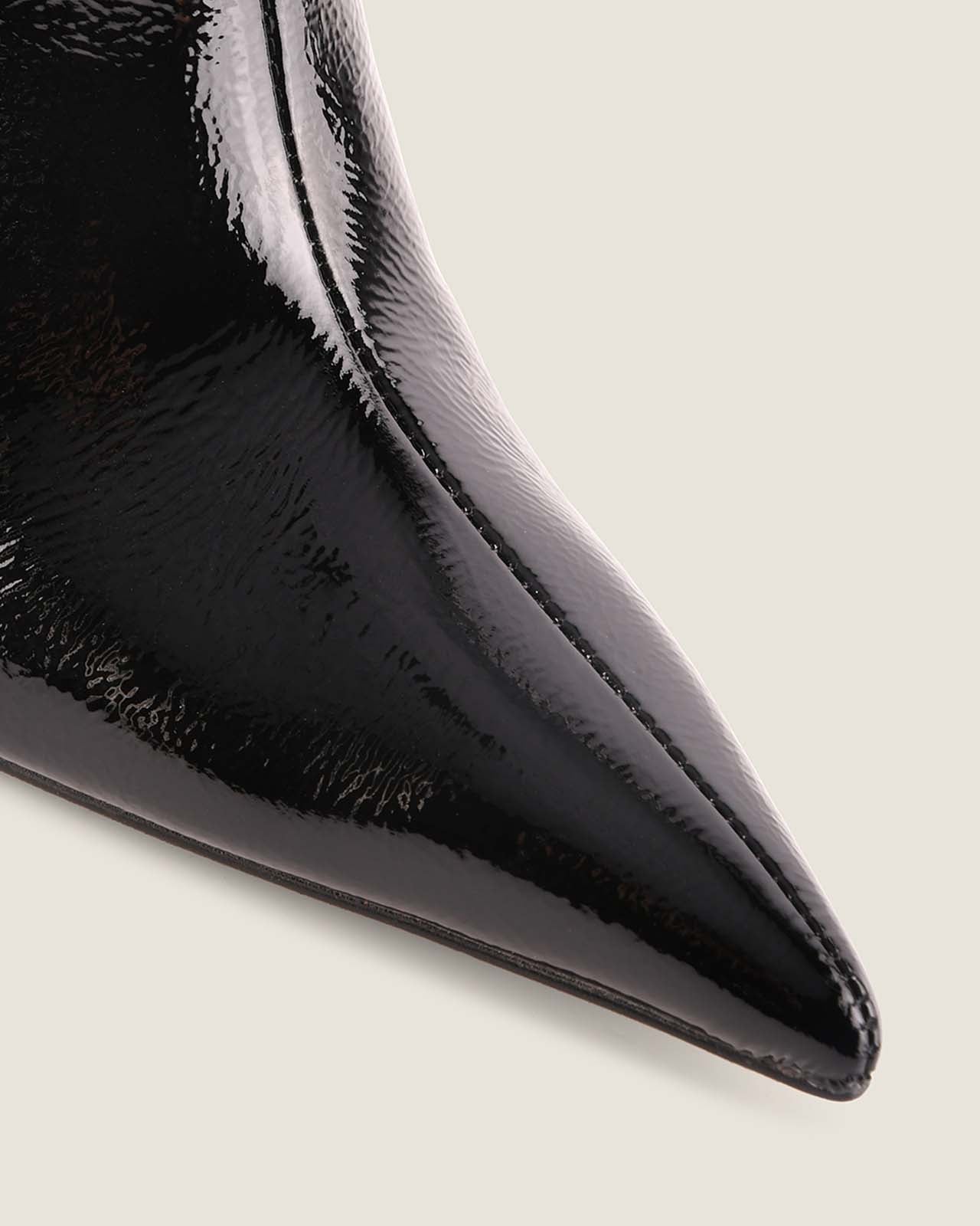 Close-up of a black patent leather shoe on a light background