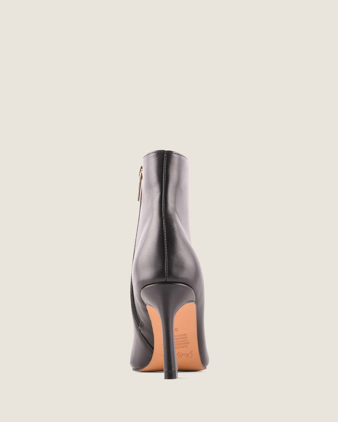 Black high-heeled boot on a light grey background