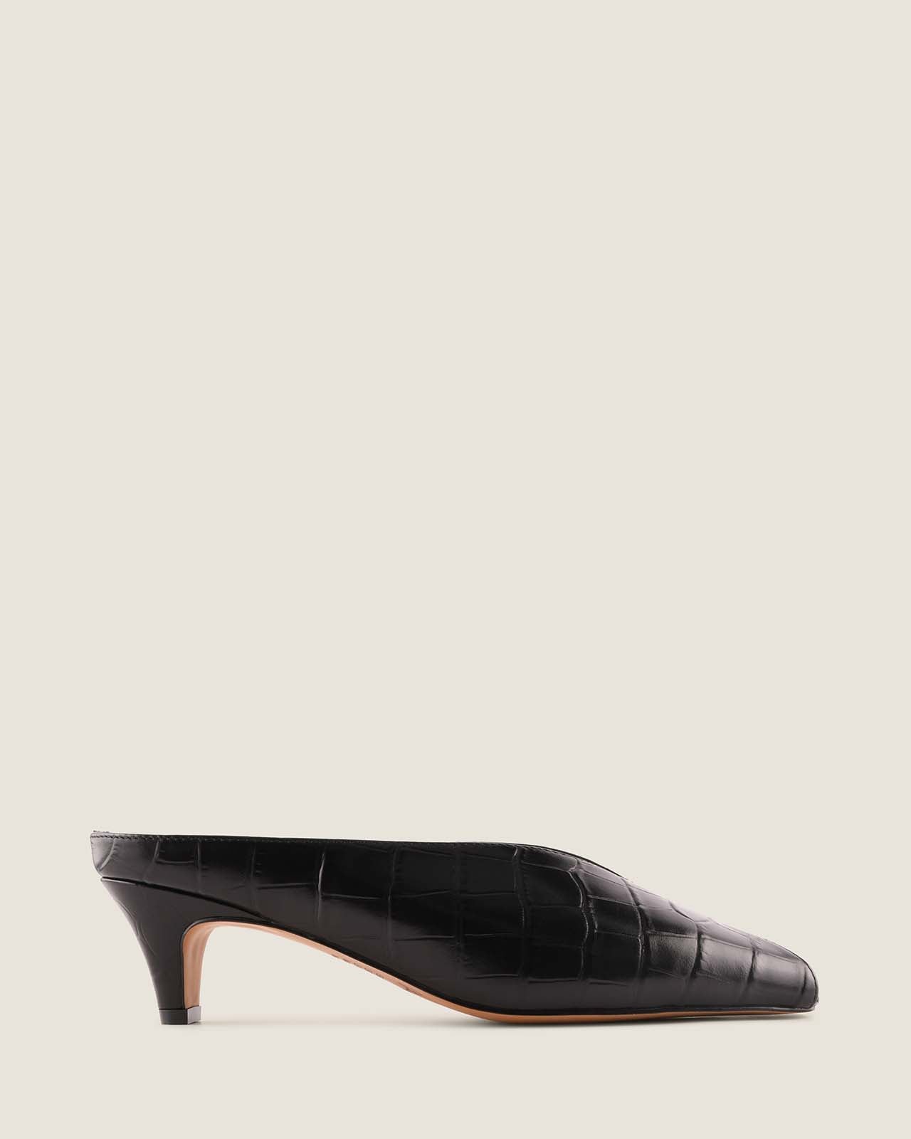 Black crocodile-patterned low heel shoe on a light beige background