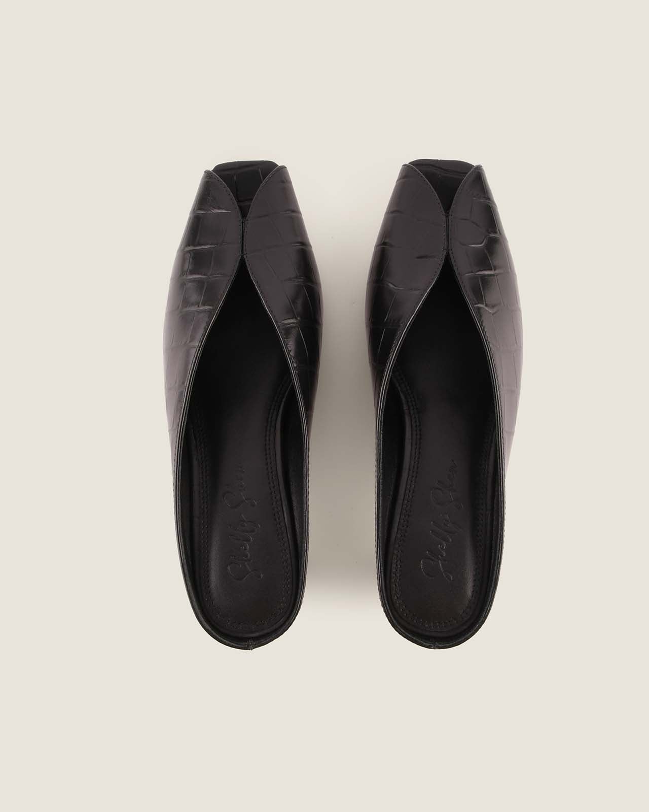 Pair of black square-toe shoes on a light grey background
