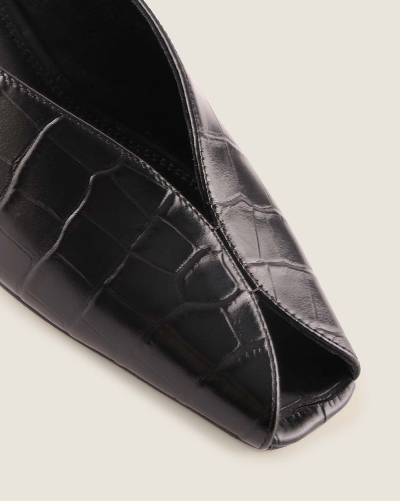 Black crocodile-patterned shoe on a light grey background