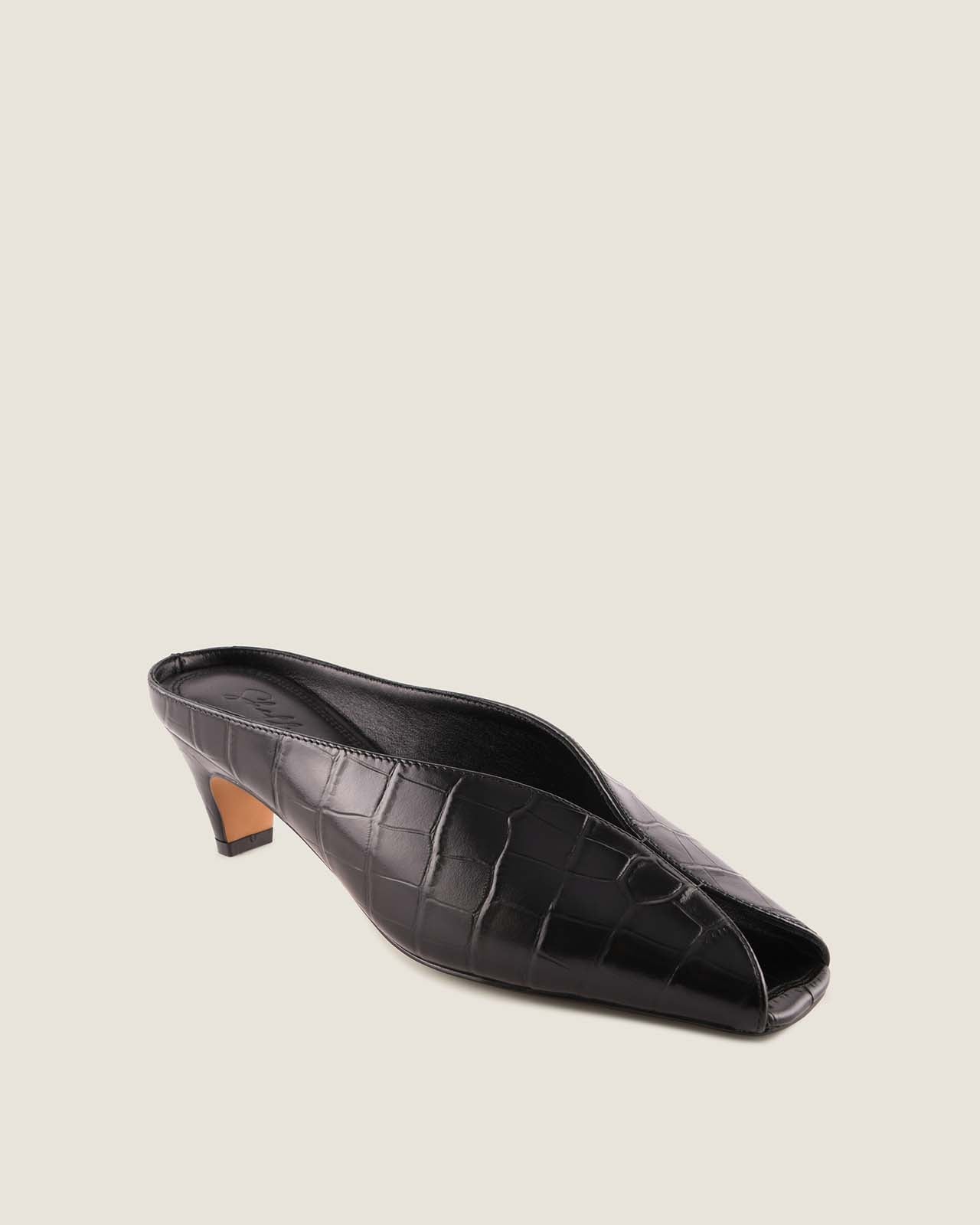 Black crocodile-patterned low-heeled shoe on a light beige background