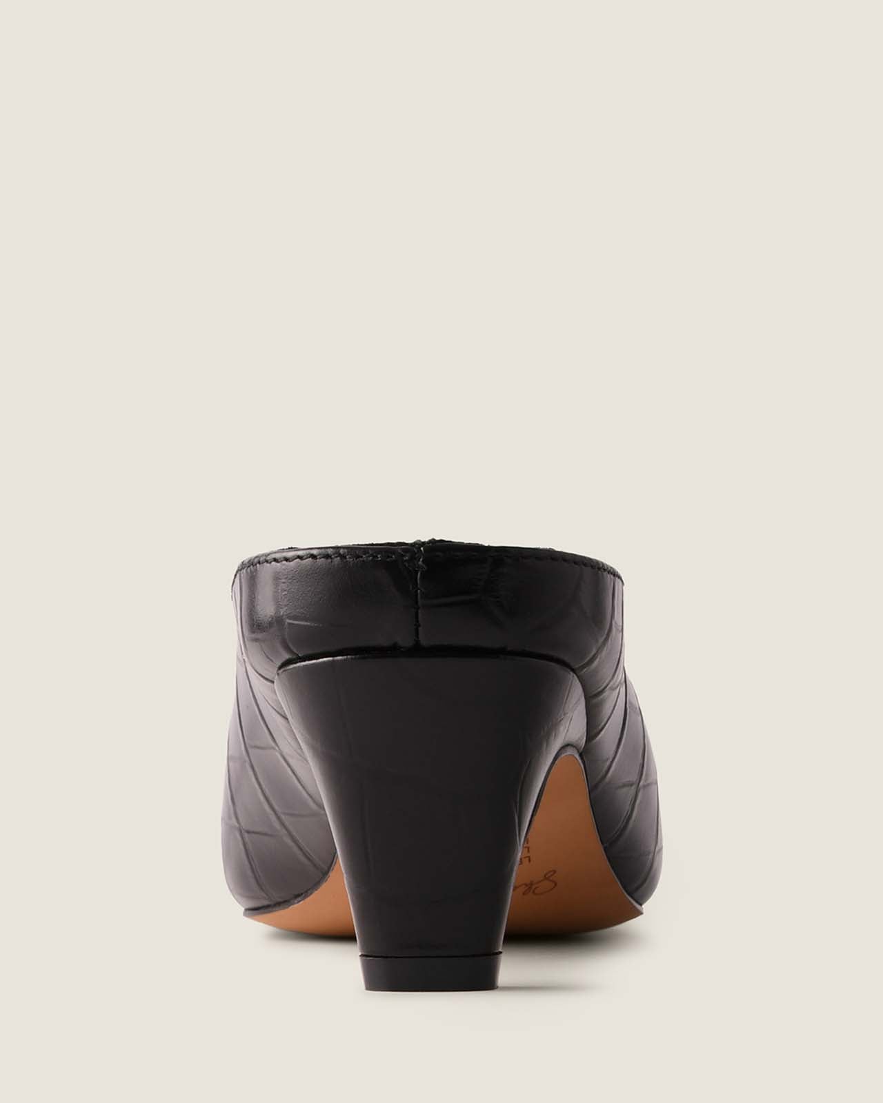 Black high-heeled shoe on a light beige background
