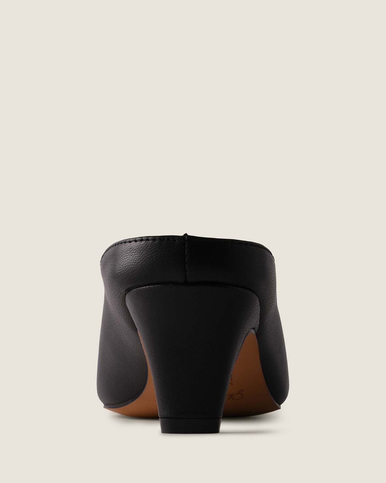 Black high-heeled shoe on a light beige background