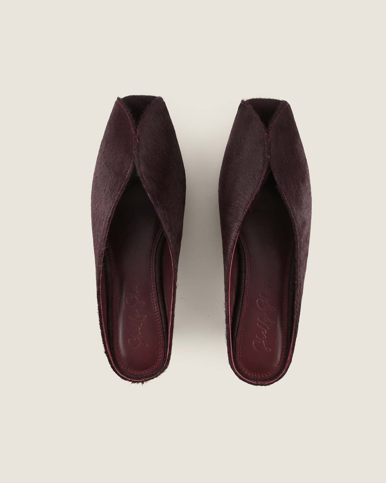 Pair of burgundy open-toe shoes on a light grey background