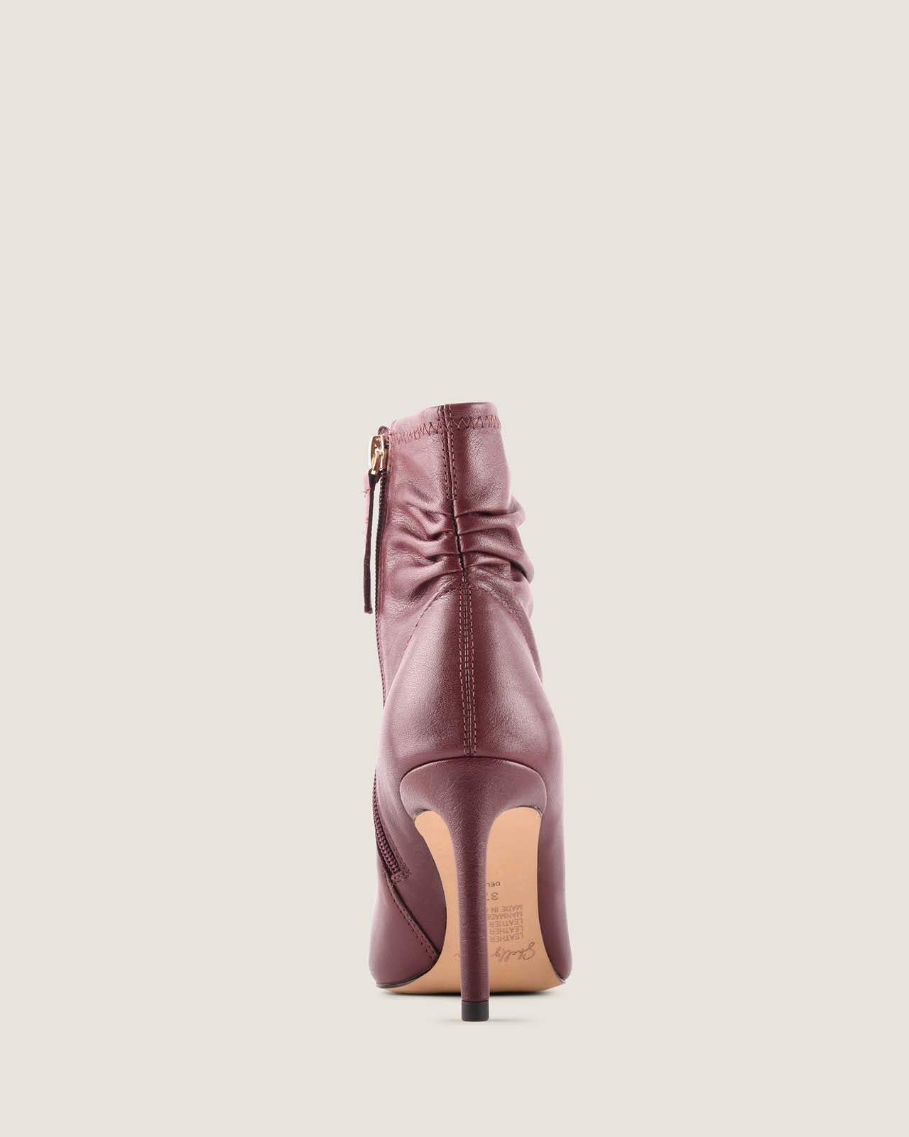 Burgundy ankle boot on a light beige background