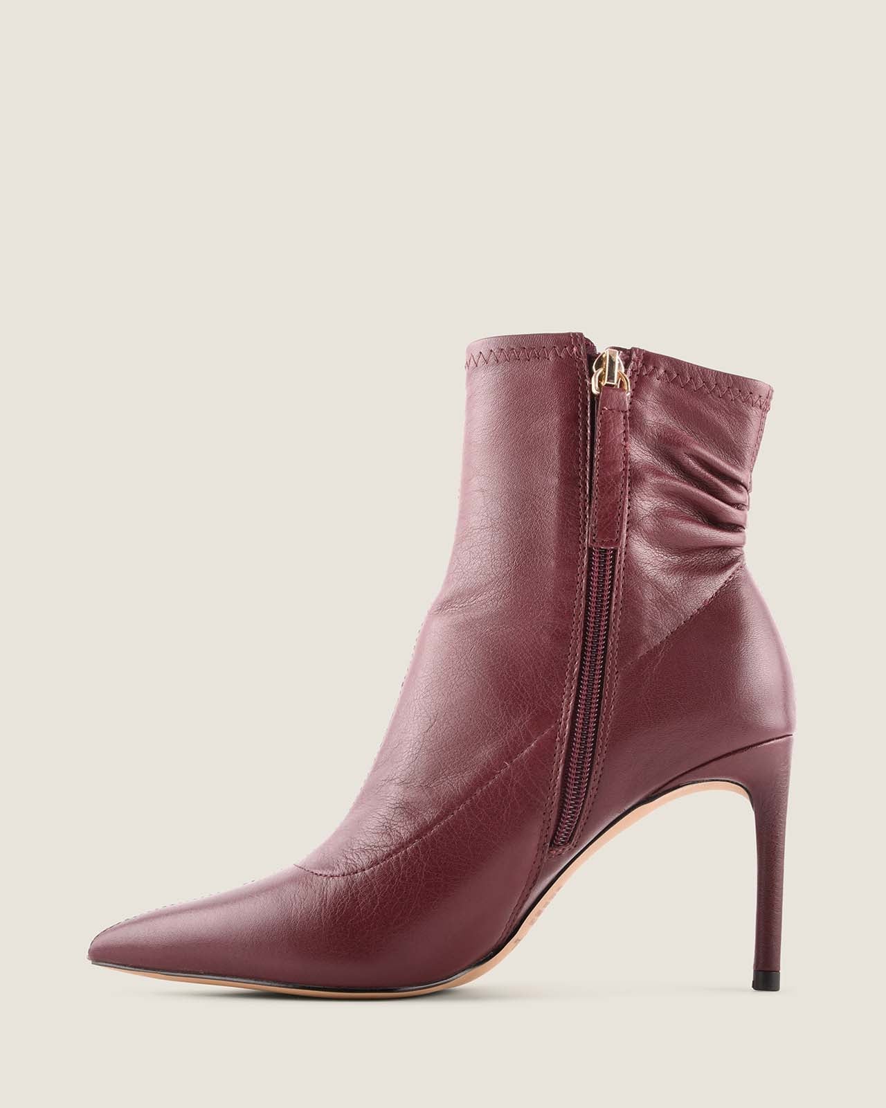 Burgundy ankle boot with a zipper on a light beige background