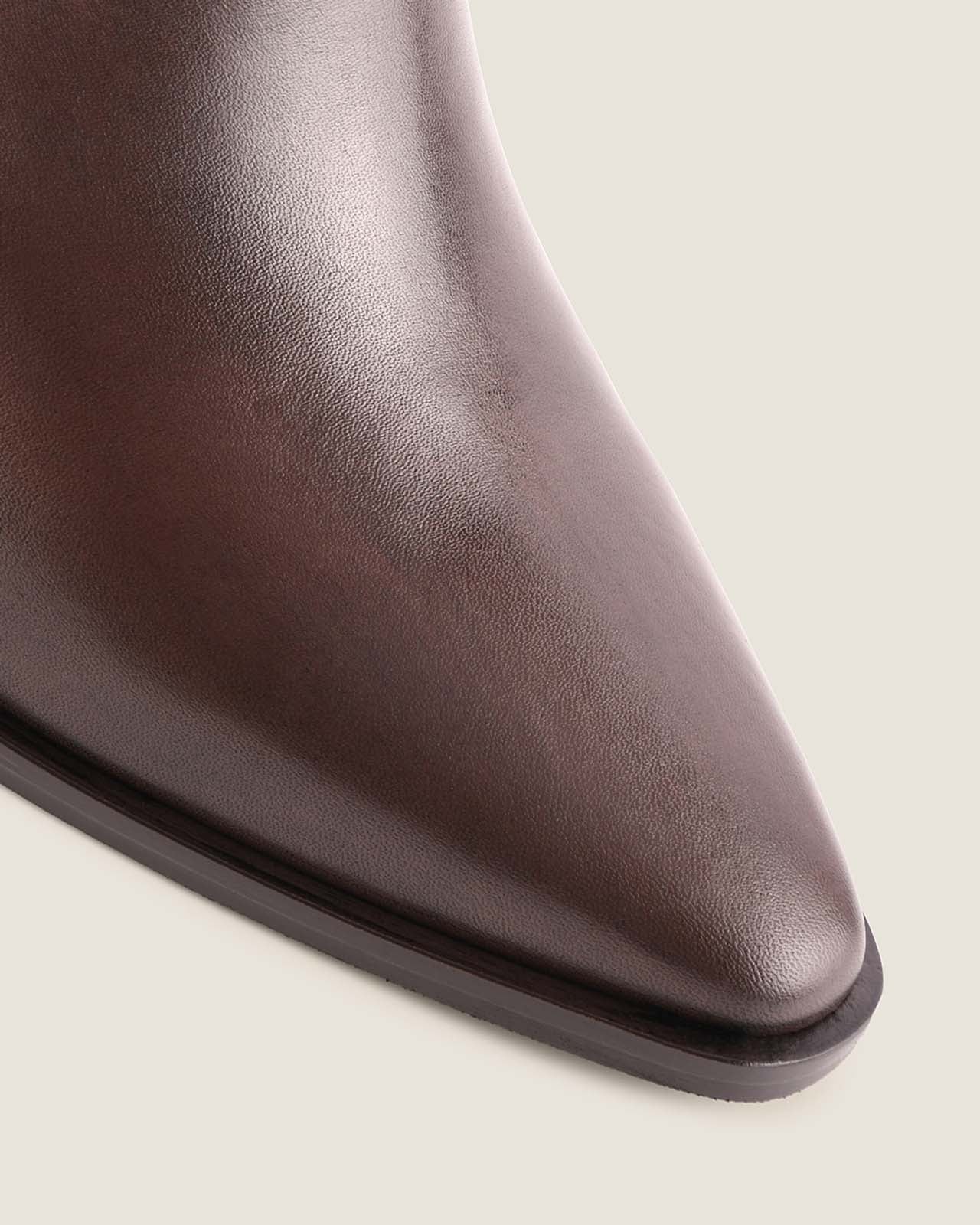 Close-up of a brown leather ankle boot on a light background