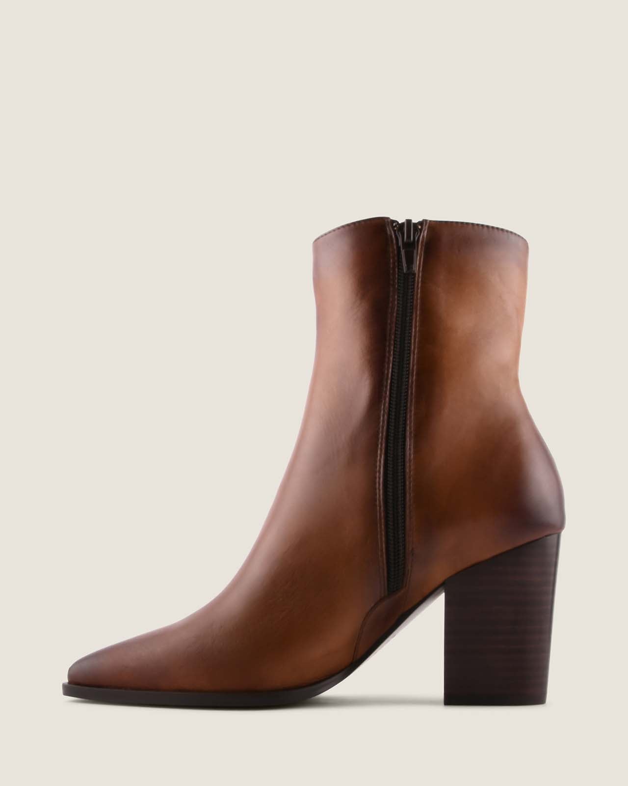 Brown leather ankle boot with a block heel on a light beige background