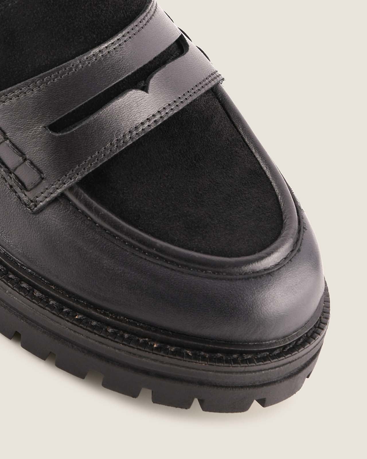 Black platform loafer shoe on a light grey background
