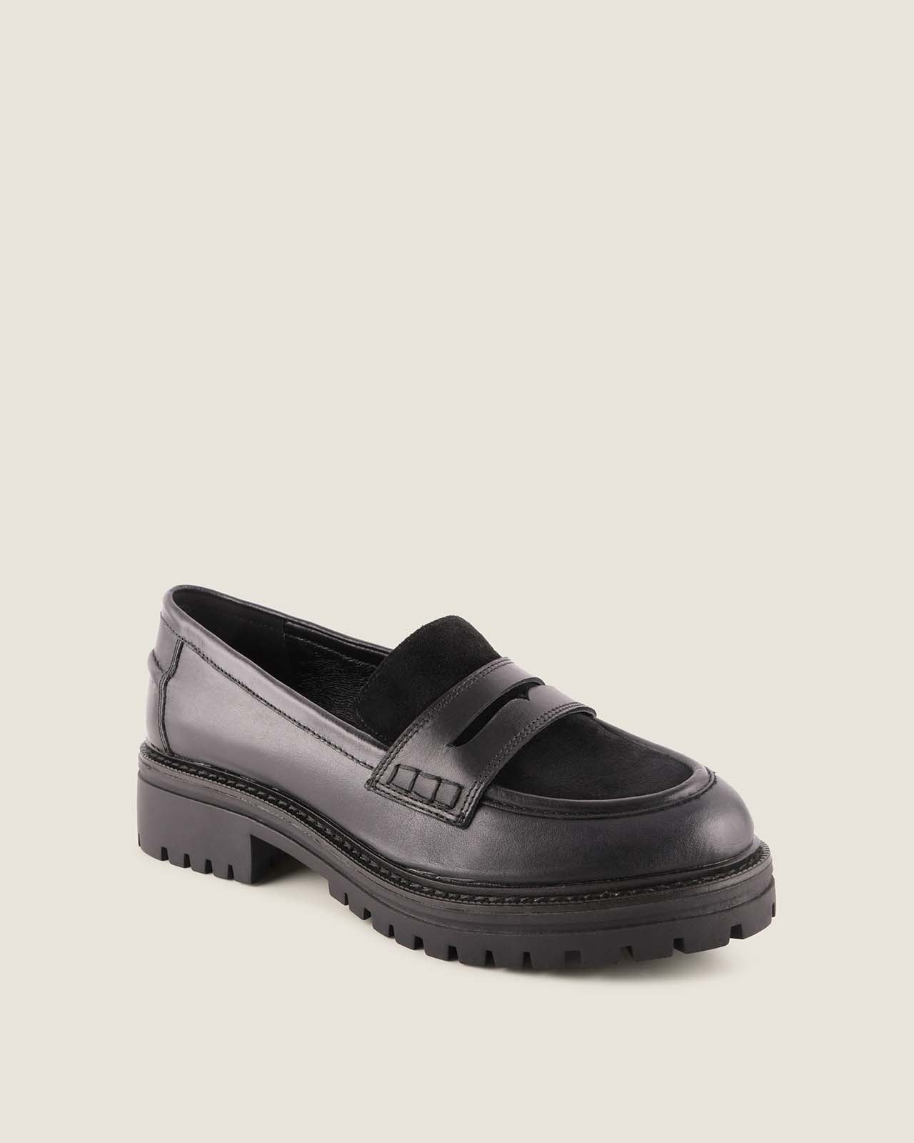 Black platform loafer shoe on a beige background