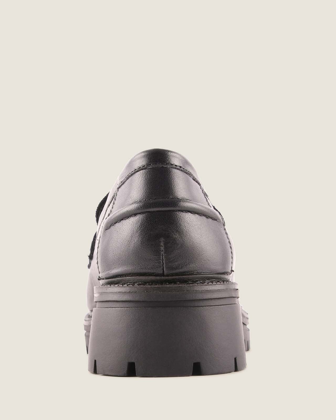 Black leather shoe on a light grey background