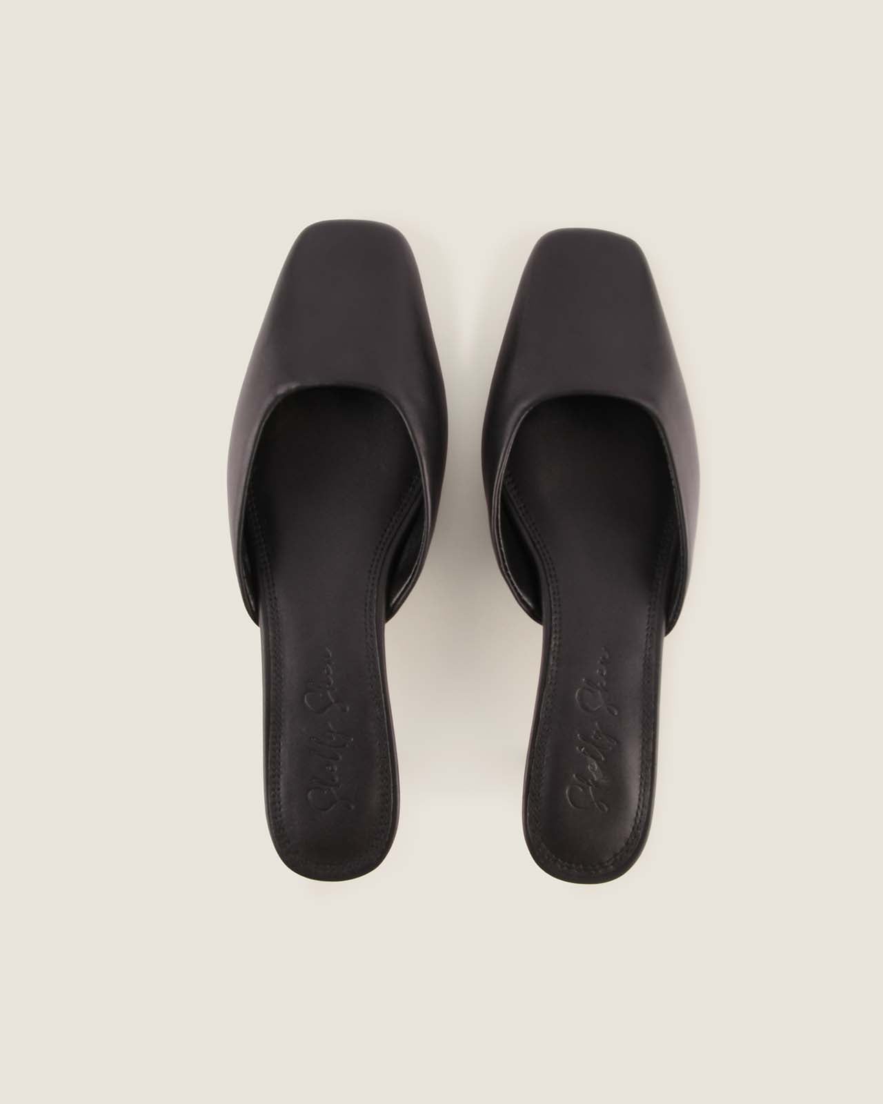 Pair of black square-toe heels on a light grey background