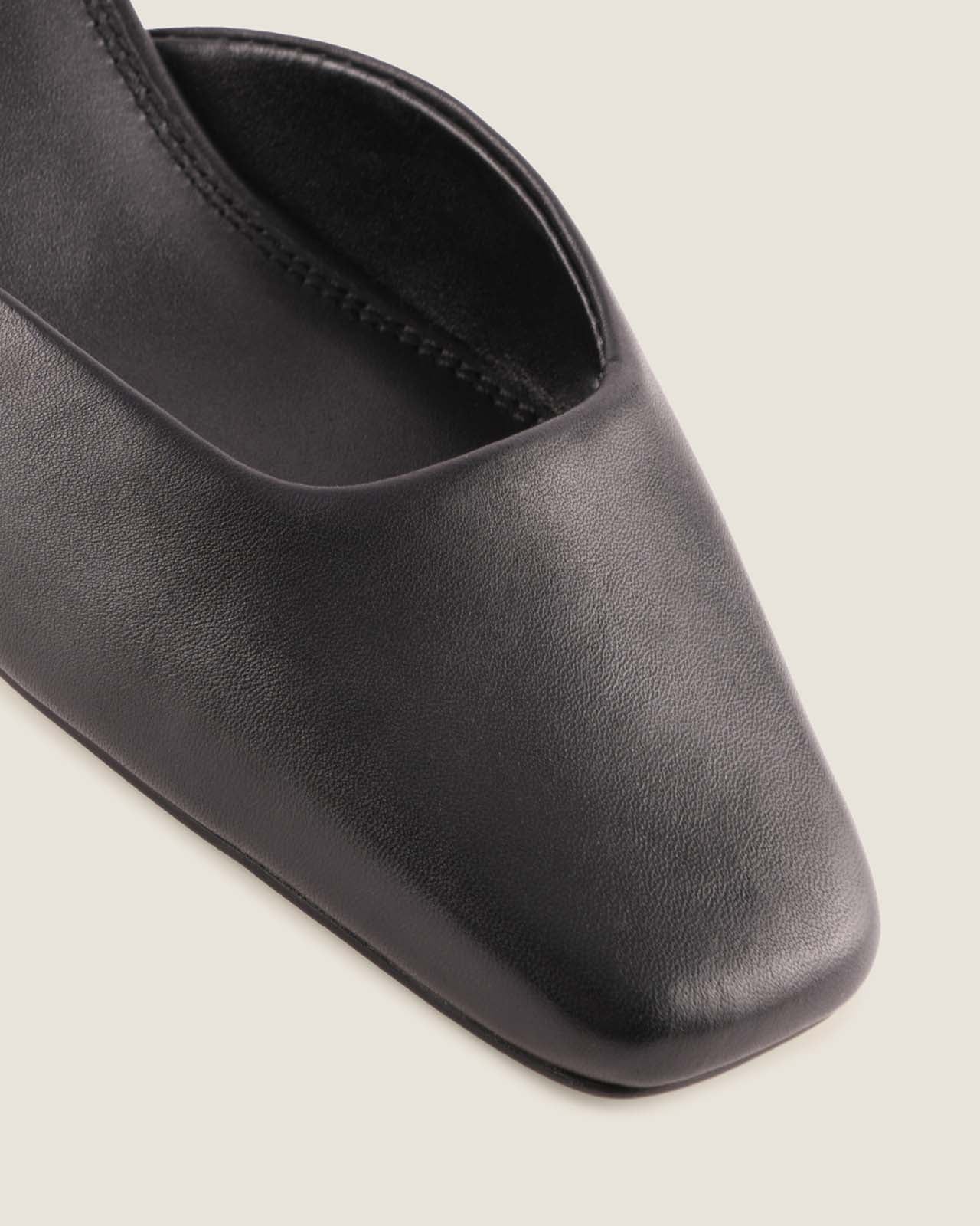 Black leather shoe with a square toe on a light grey background