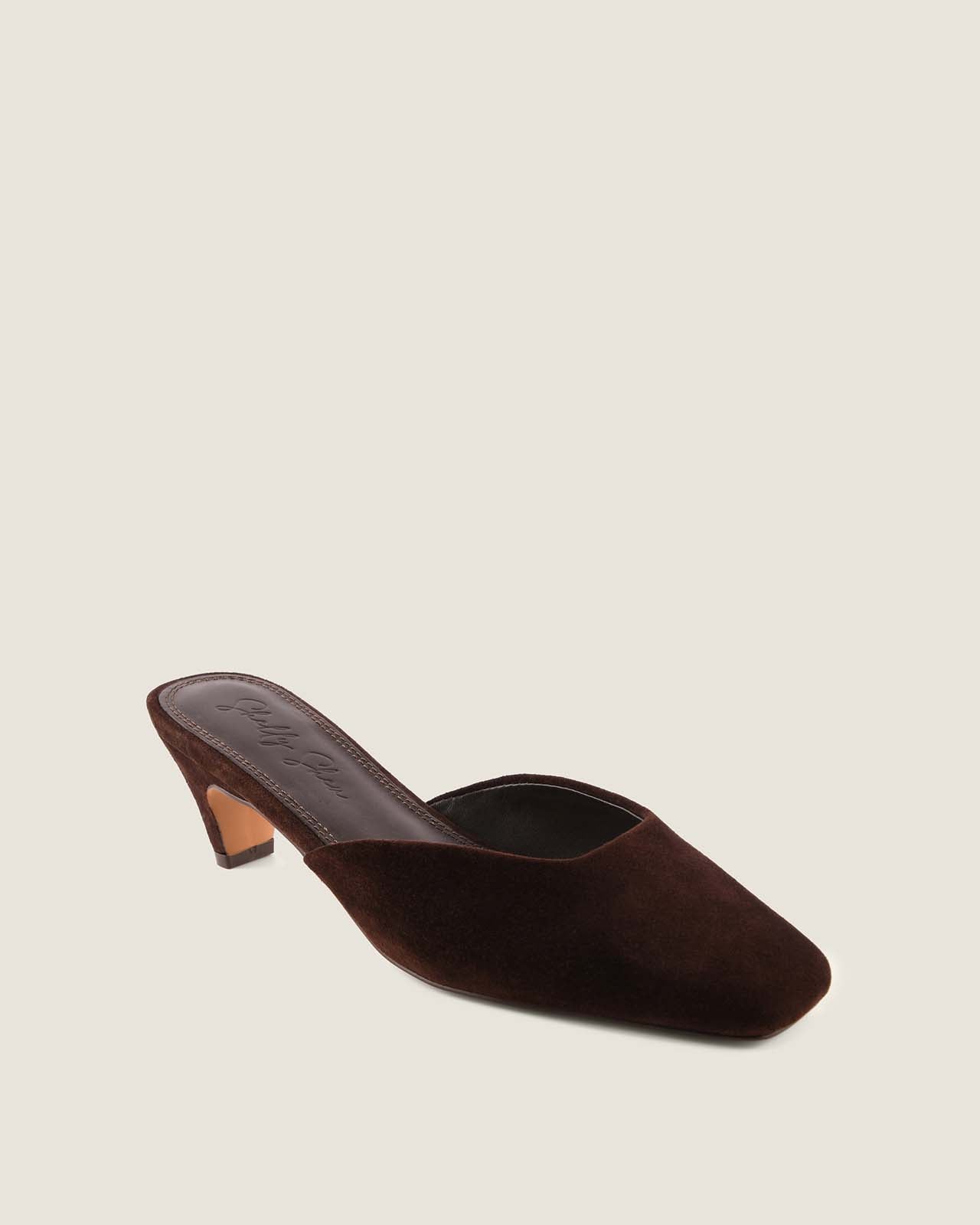 Brown suede heeled shoe on a beige background