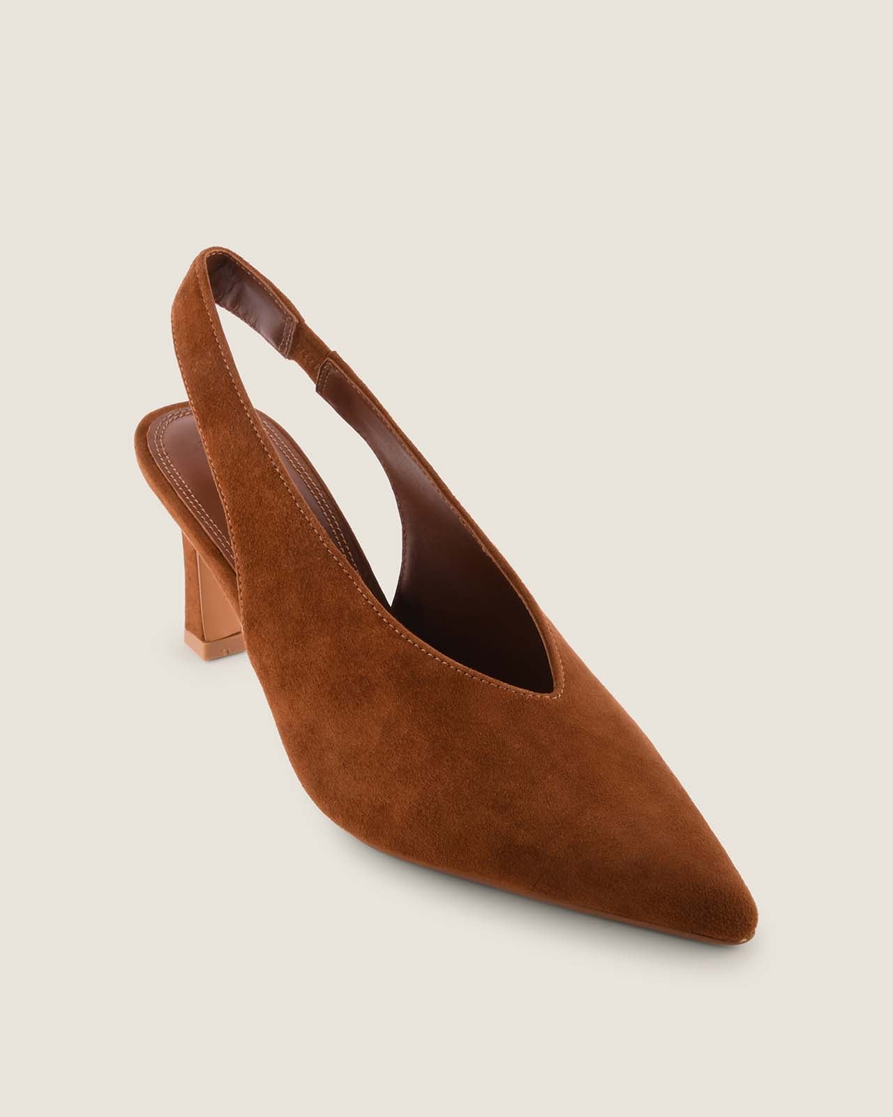 Tan suede slingback shoe on a light beige background