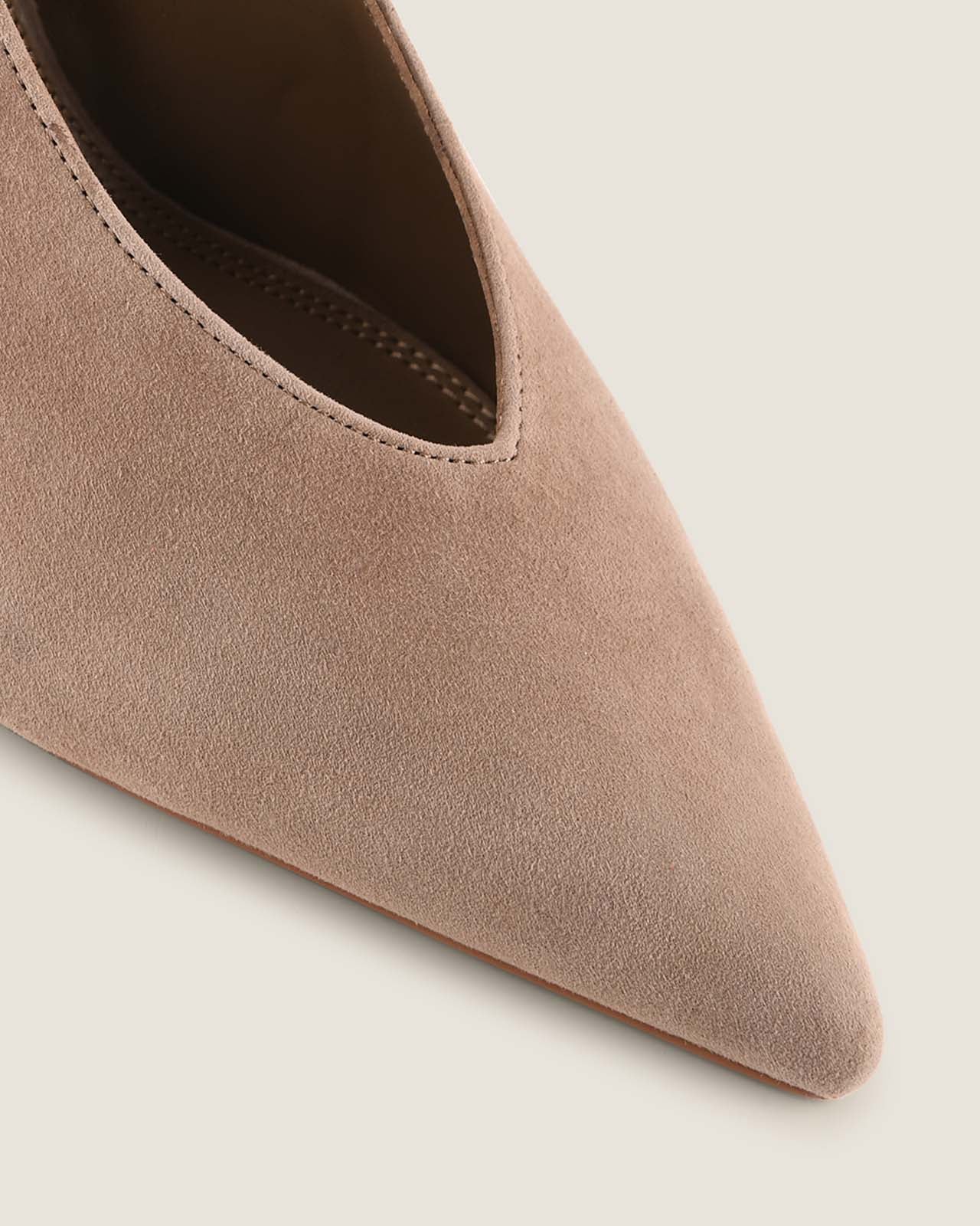 Close-up of a taupe pointed-toe shoe on a light background