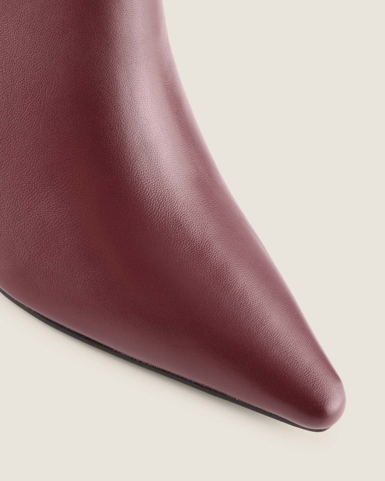 Close-up of a burgundy leather shoe on a light beige background