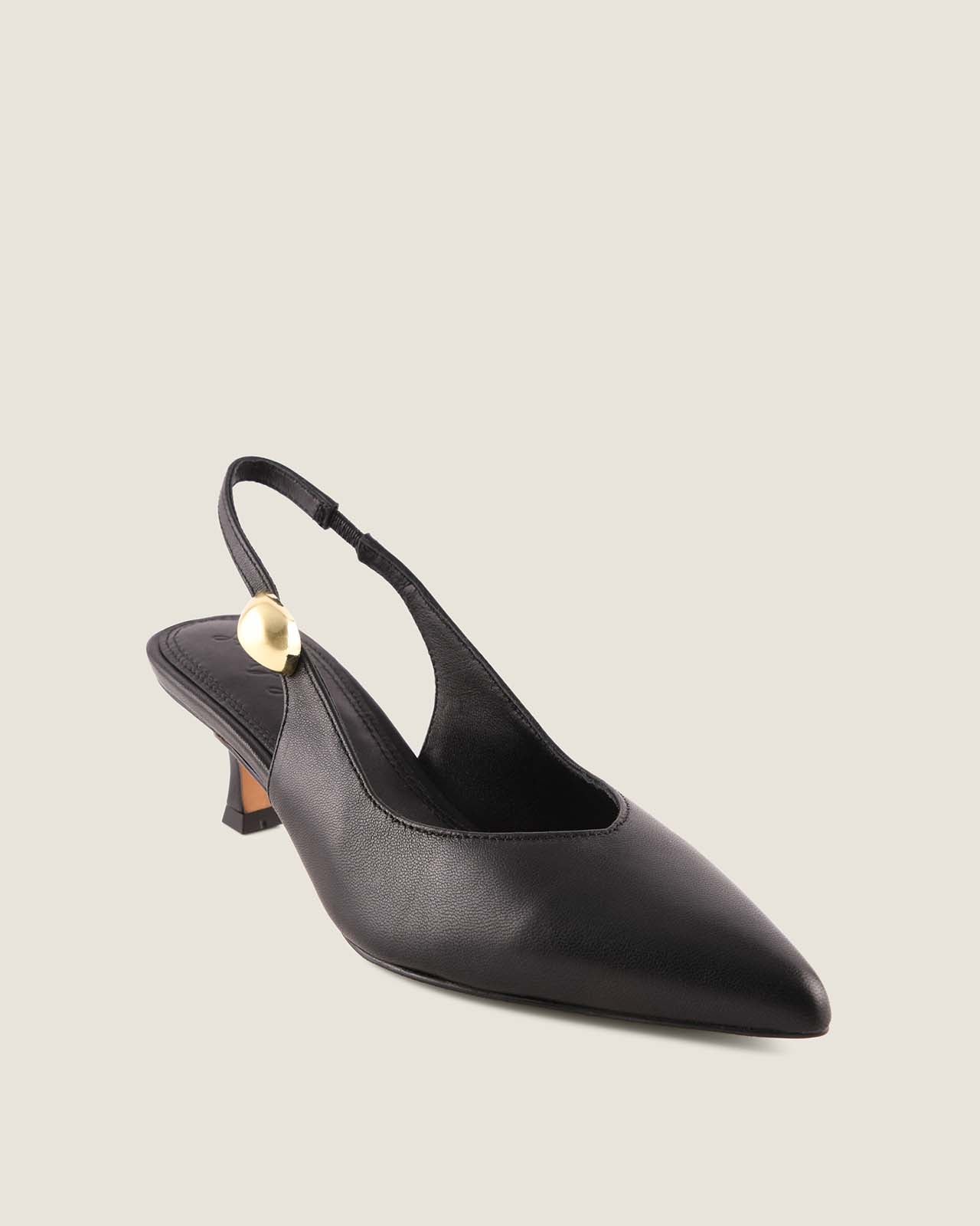 Black slingback heel with a gold ornament detail on a light beige background