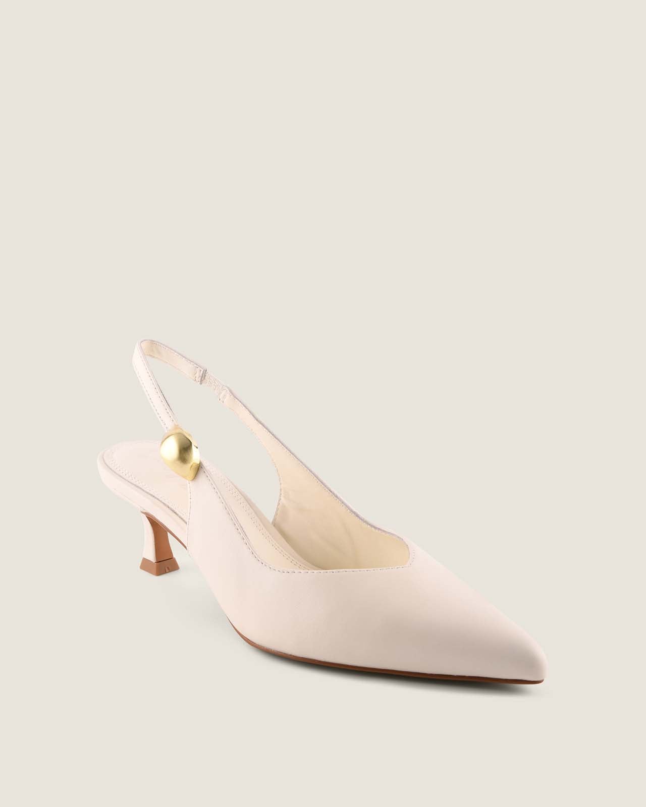 White leather slingback heel with a gold ornament detail on a light beige background