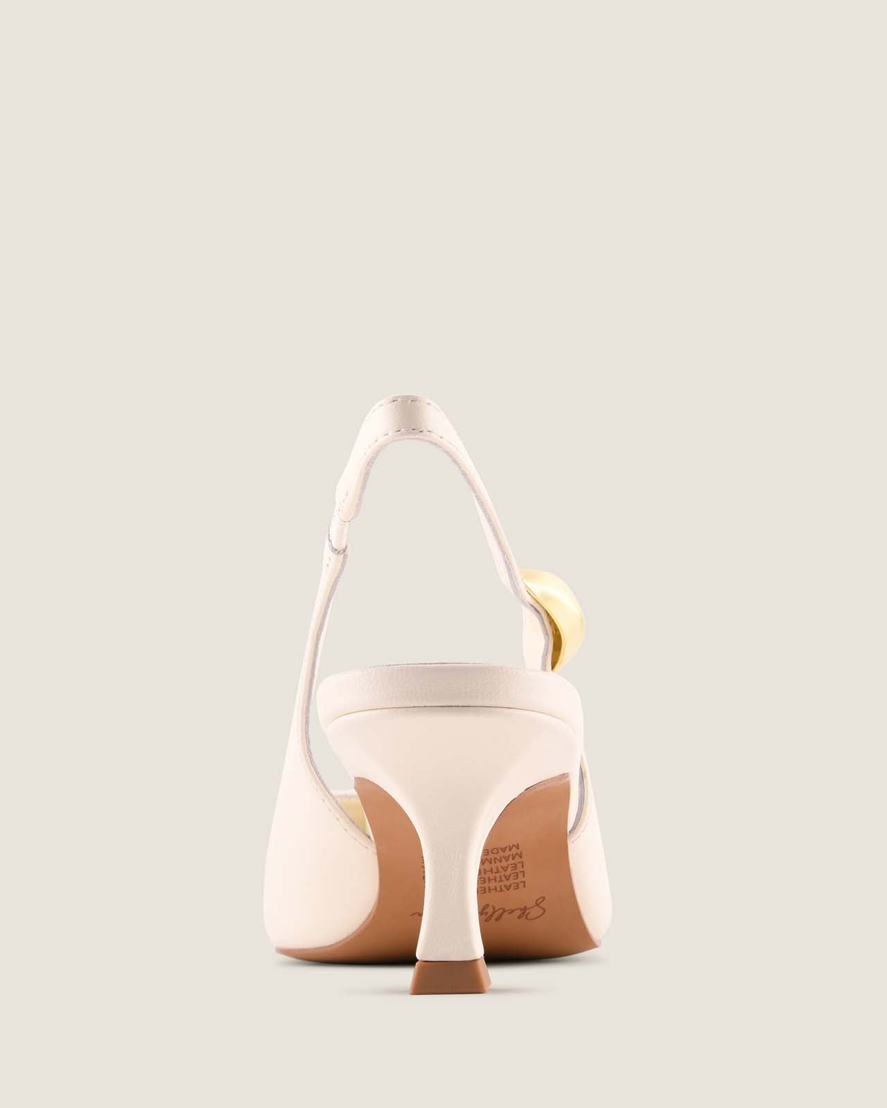 White leather slingback heel with a gold ornament detail on a light beige background
