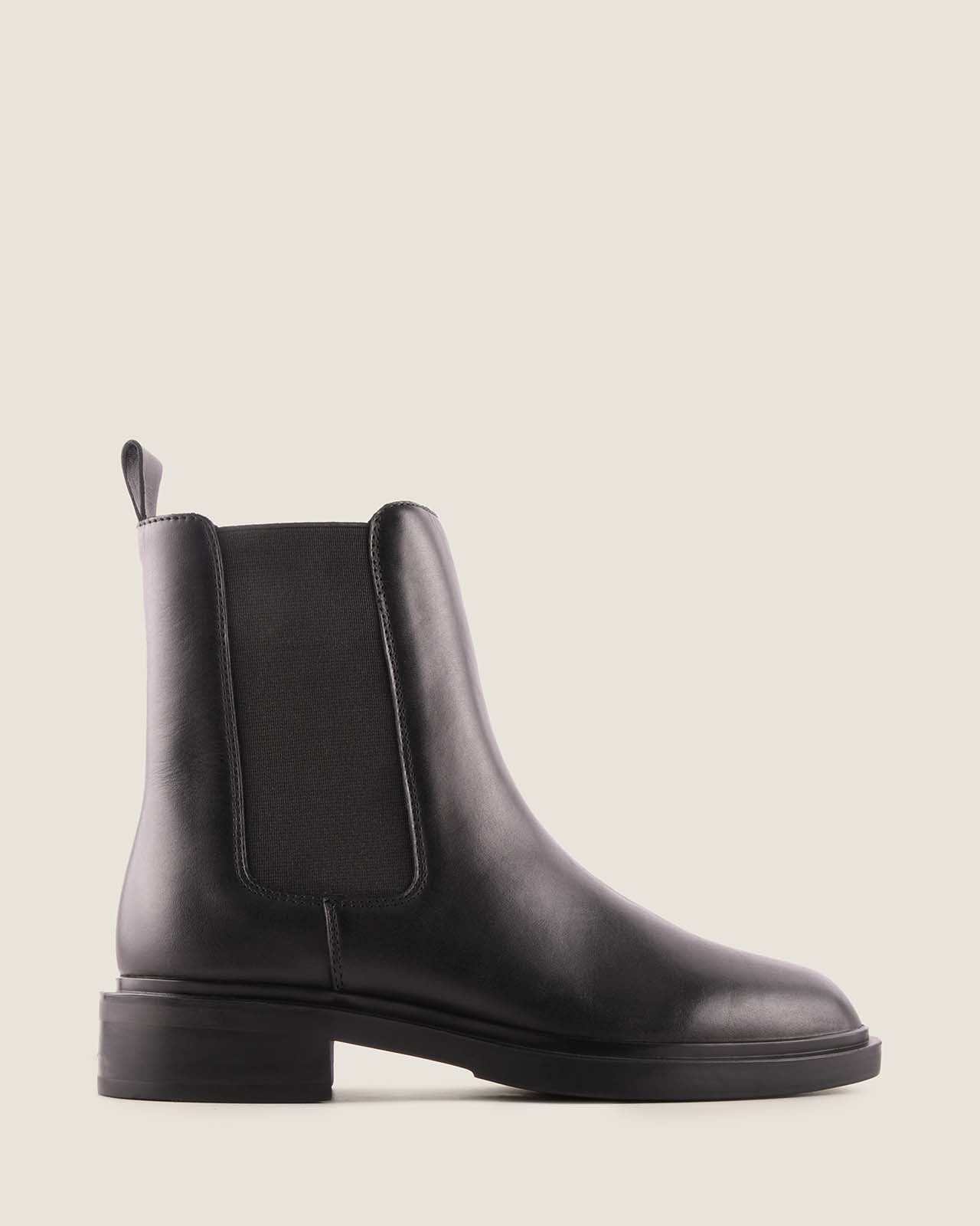 Black leather boot on a light grey background