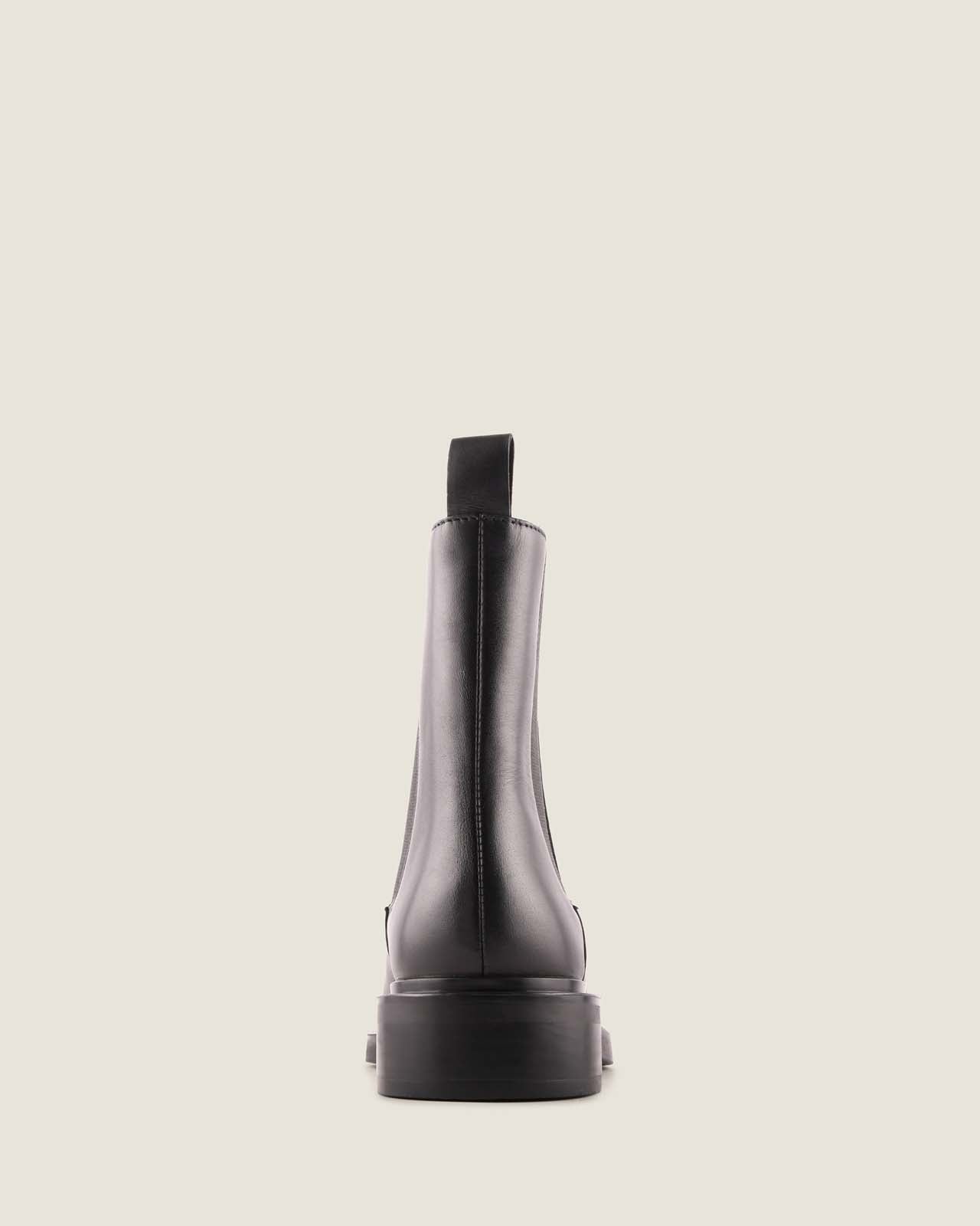Back of a black leather boot on a light grey background