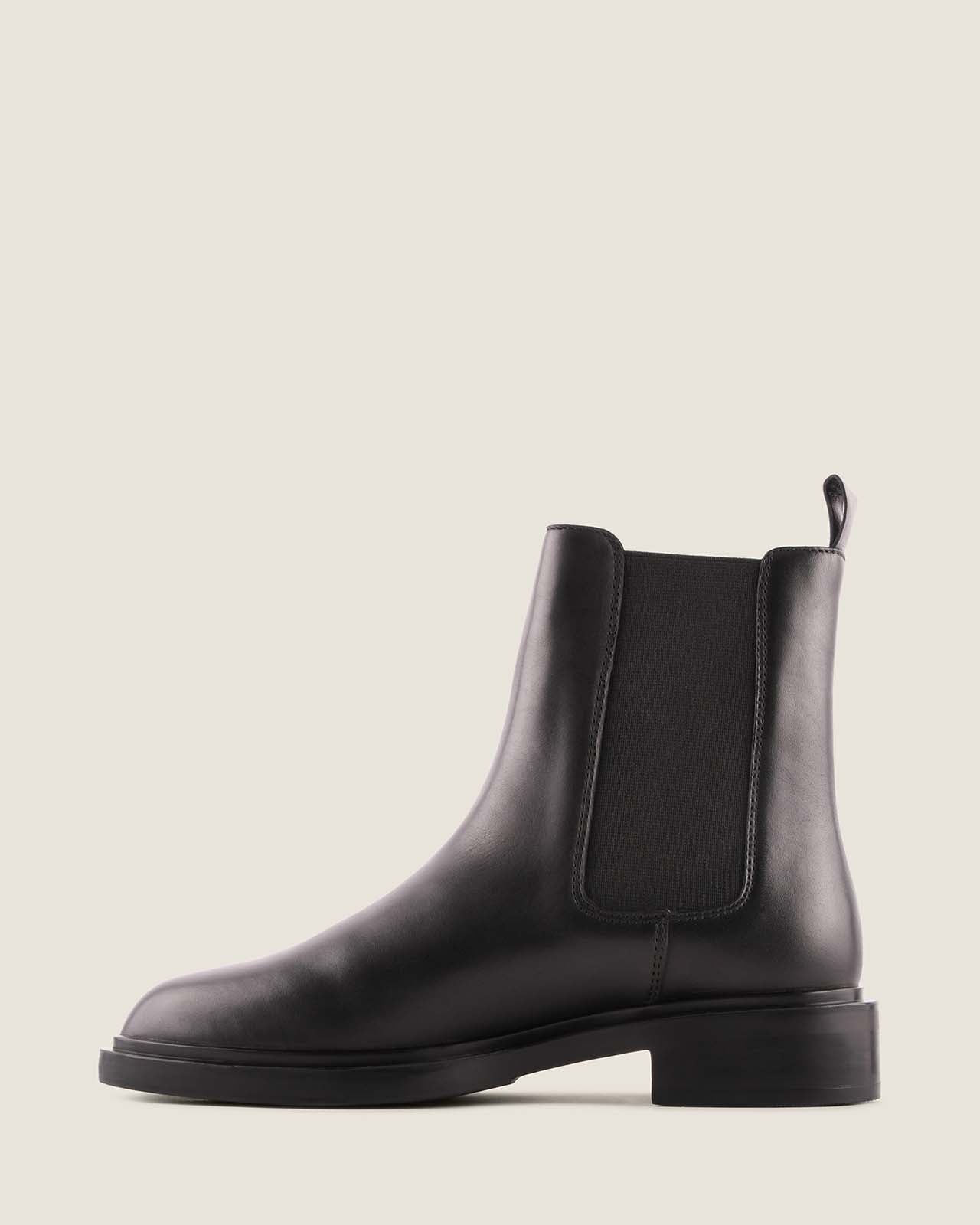 Black leather boot on a light grey background