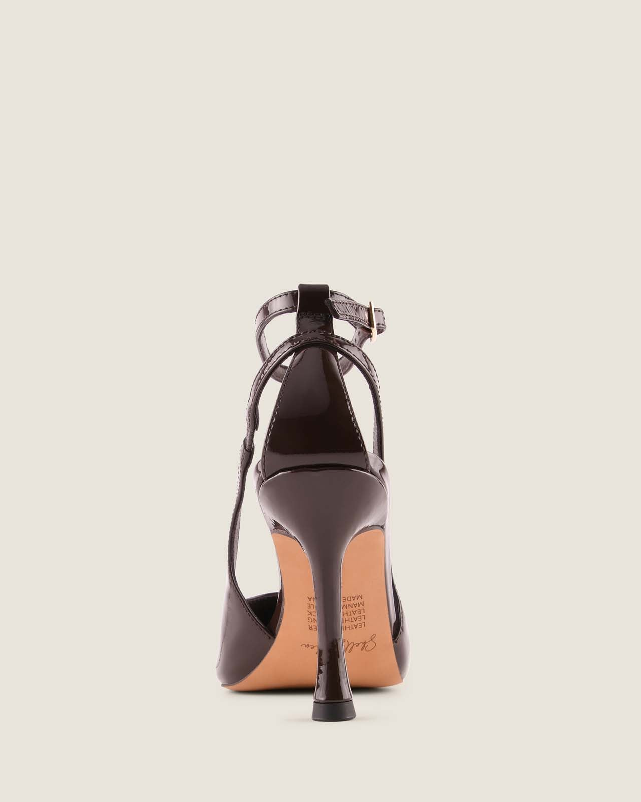 Brown patent leather high-heeled shoe on a beige background