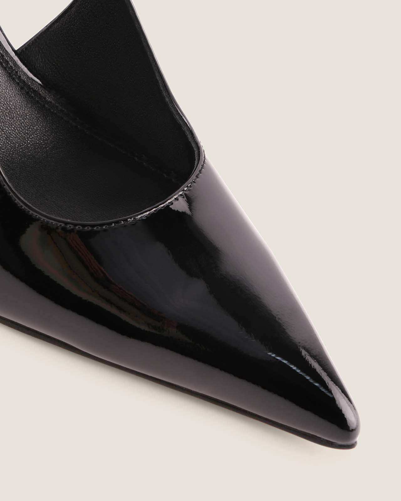 Black pointed-toe shoe on a light beige background