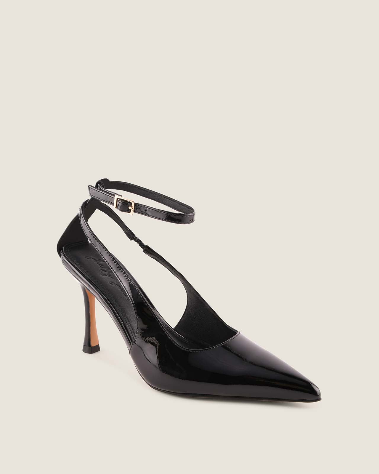 Black patent leather high-heeled shoe with ankle strap on a light grey background