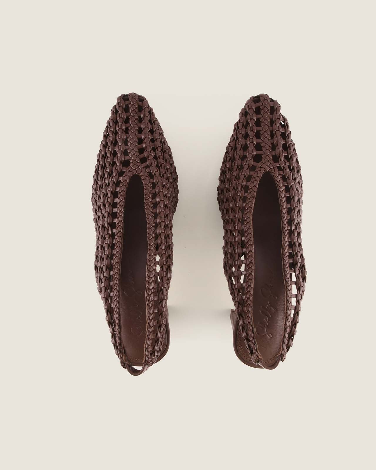 Pair of brown woven shoes on a light beige background