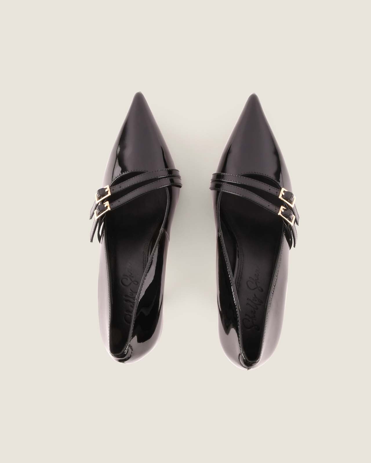 Pair of black pointed-toe shoes with gold accents on a light grey background