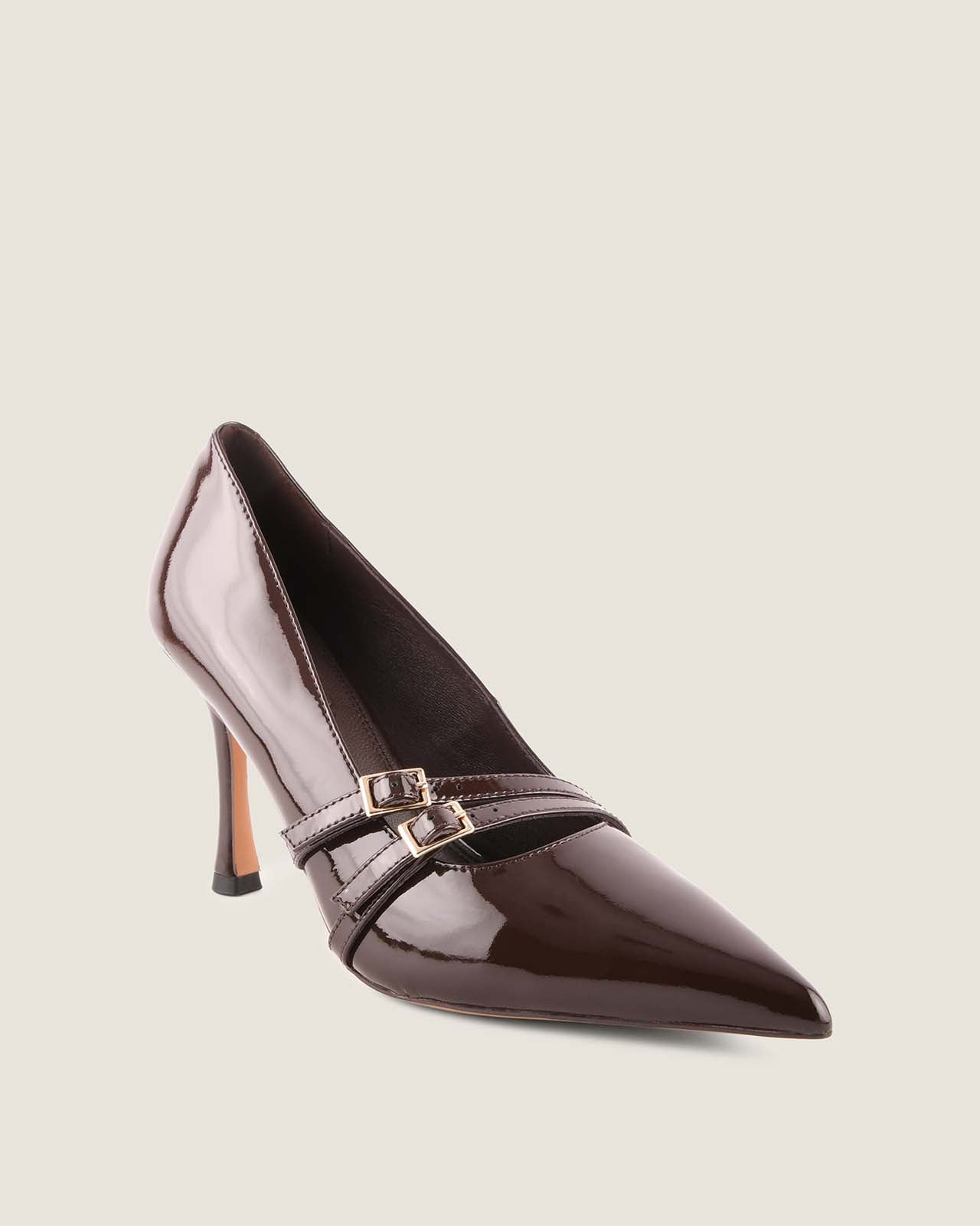 Brown patent leather high-heeled shoe with a strap on a light beige background